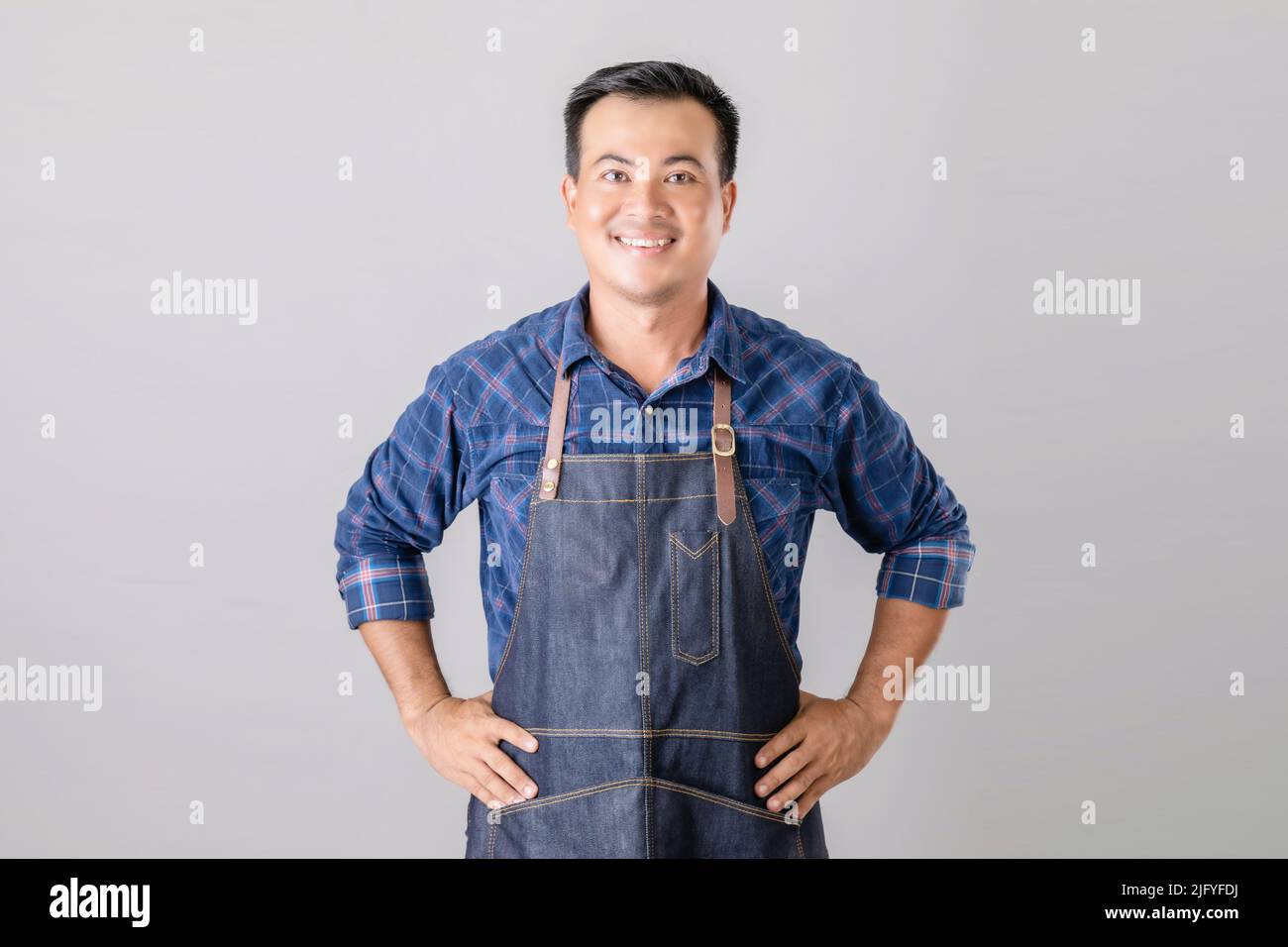 Portrait Asian man in Barista Uniform stehend im Studio isoliert auf grauem Hintergrund Stockfoto