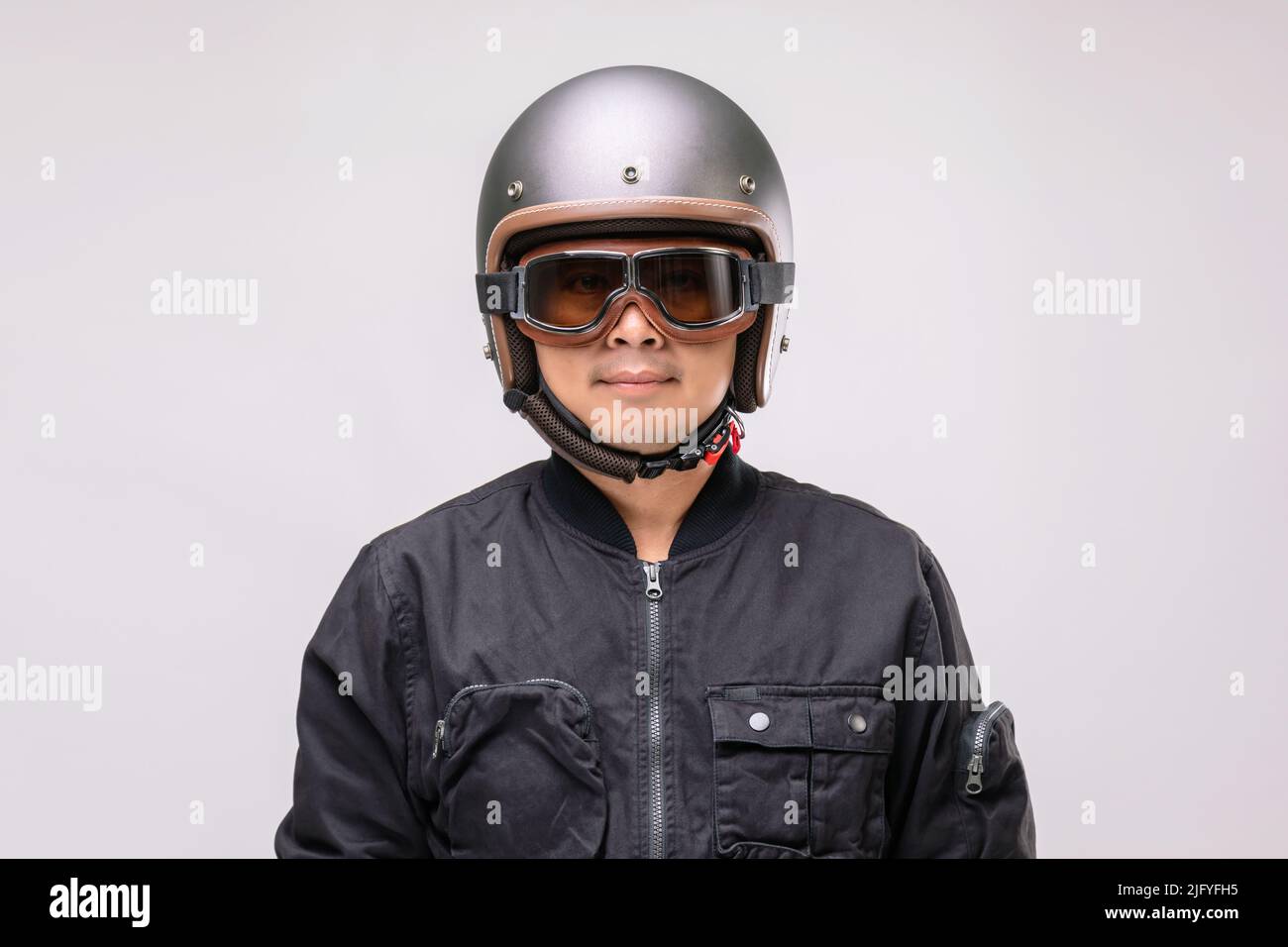 Motorradfahrer oder Fahrer mit Vintage-Helm. Sicheres Fahrkonzept. Studio auf grauem Hintergrund aufgenommen Stockfoto