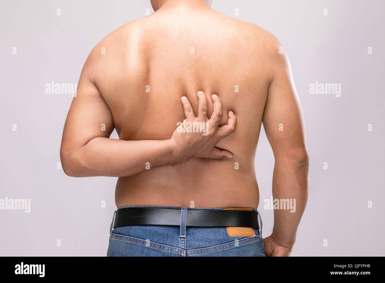 Körperpflege oder Juckreiz oder Tinea cruris Konzept : Porträt von Menschen mit Händen zu kratzen auf dem Rücken. Studio auf grauem Hintergrund aufgenommen Stockfoto