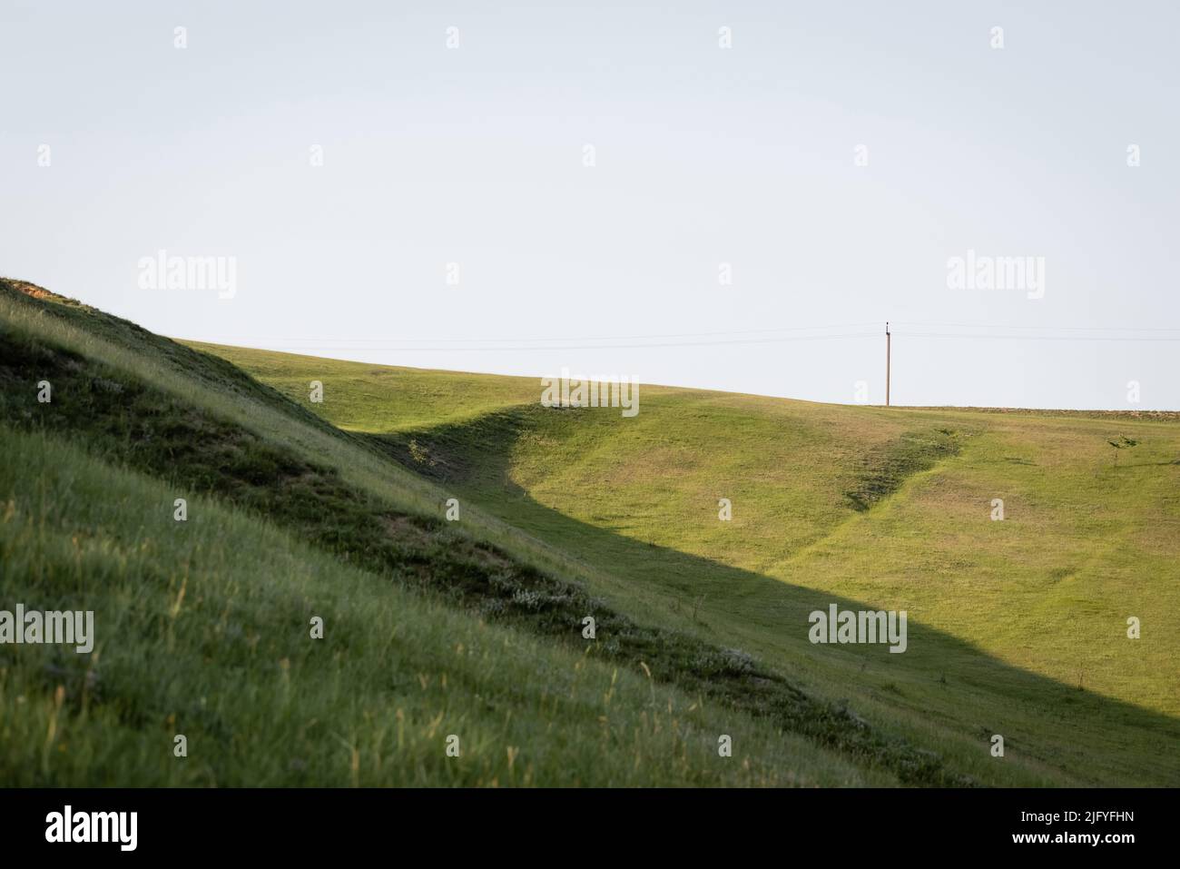 Grasbewachsene Hänge auf dem Land unter klarem, wolkenlosem Himmel Stockfoto