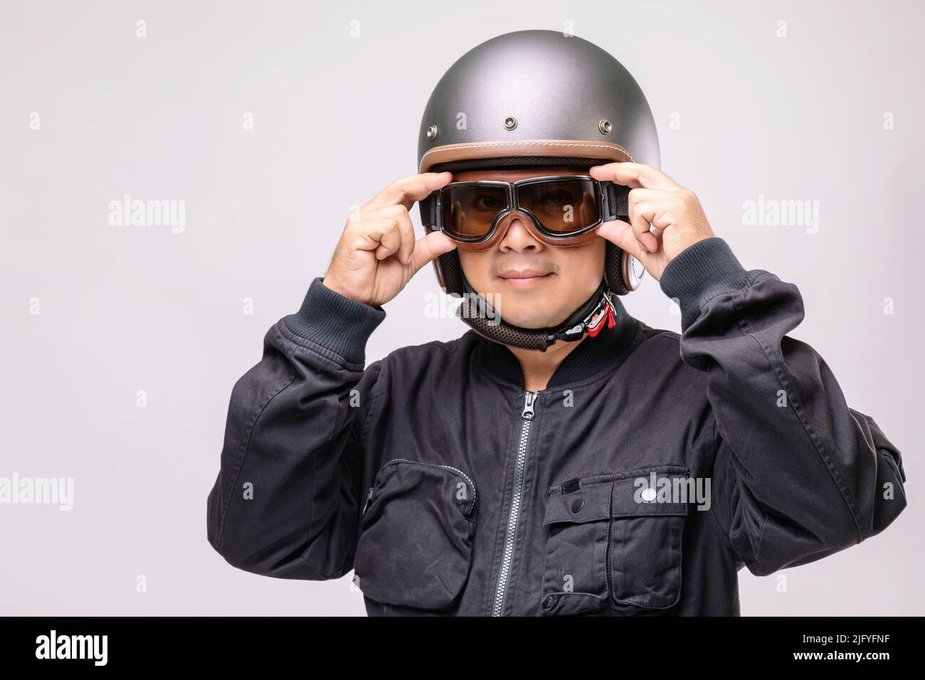 Motorradfahrer oder Fahrer mit Vintage-Helm. Konzept der „Safe Ride“-Kampagne. Studioaufnahme isoliert auf grauem Hintergrund Stockfoto
