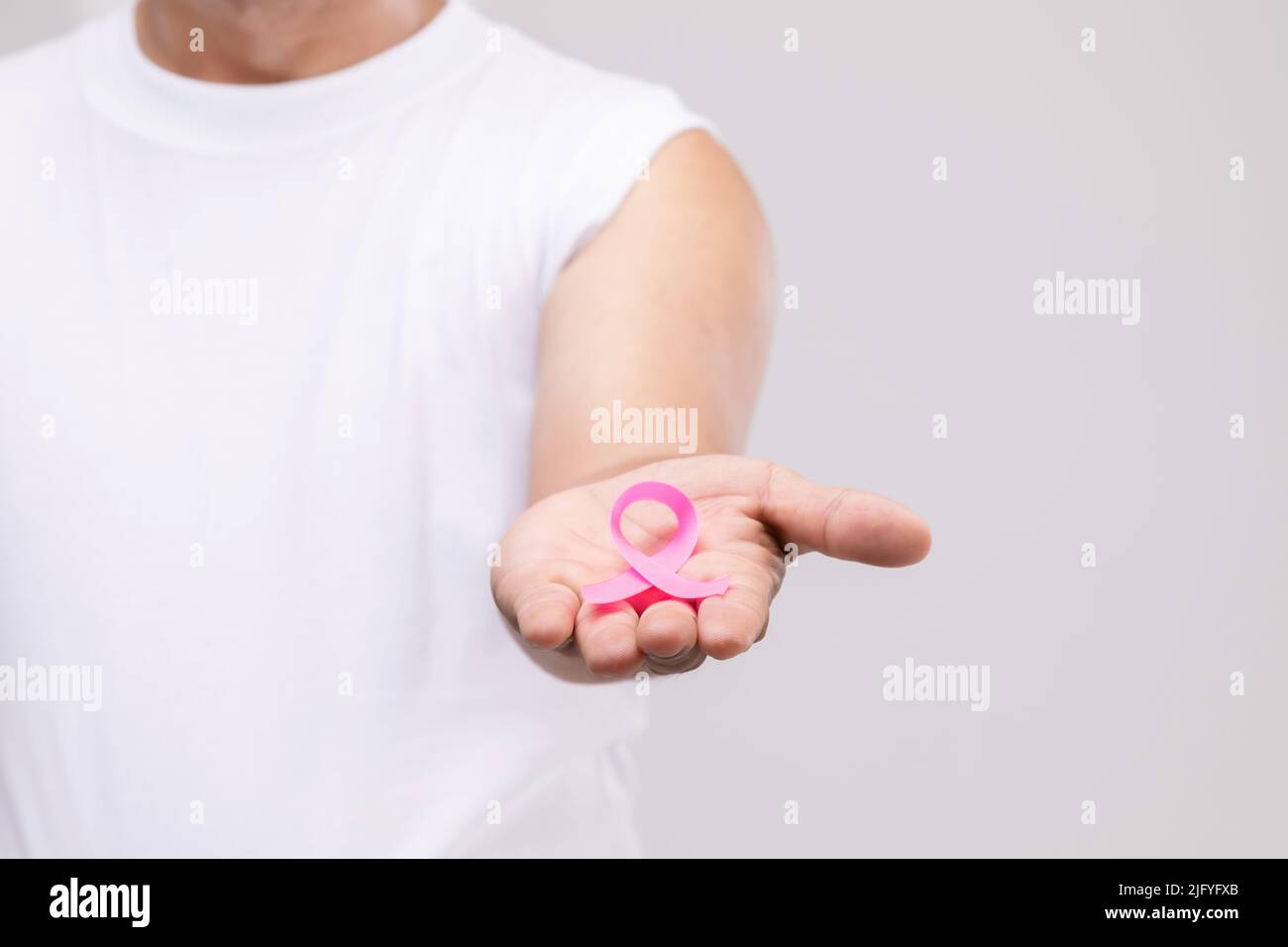 Brustkrebs bei Männern Konzept : Portrait asiatischer Mann und rosa Band das Symbol der Brustkrebs-Kampagne. Studioaufnahme isoliert auf grauem Hintergrund Stockfoto