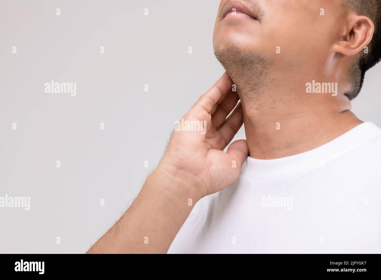 Lymphom bei Männern Konzept : Portrait asiatischen Mann ist auf seinem Hals an Lymphknoten Position berühren. Studioaufnahme isoliert auf grauem Hintergrund Stockfoto