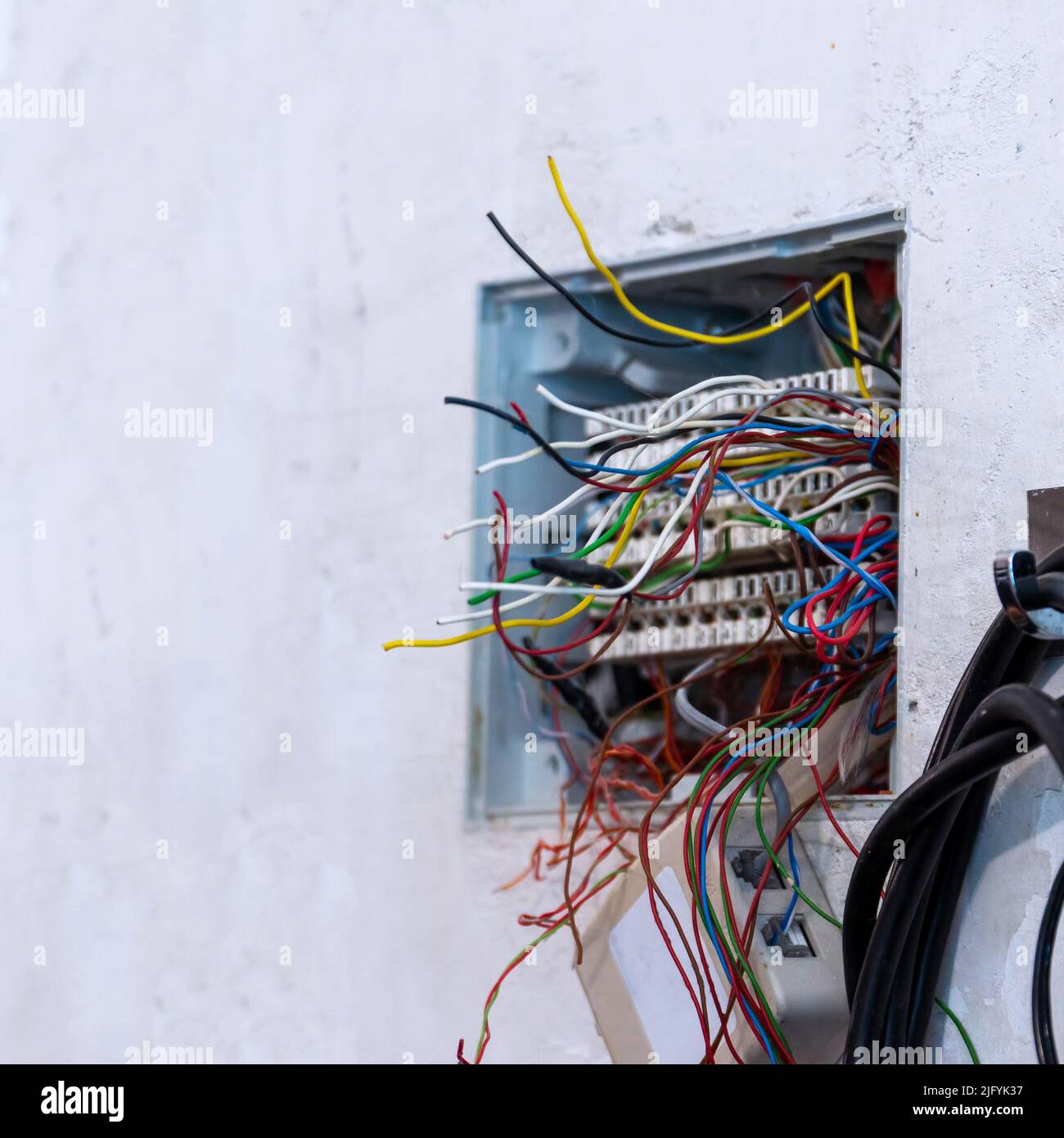 Offene Anschlussdose mit hervorstehenden Drähten, vorbereitet für die Montage und den Anschluss von Telefon- und Computerkabeln. Selektiver Fokus Stockfoto