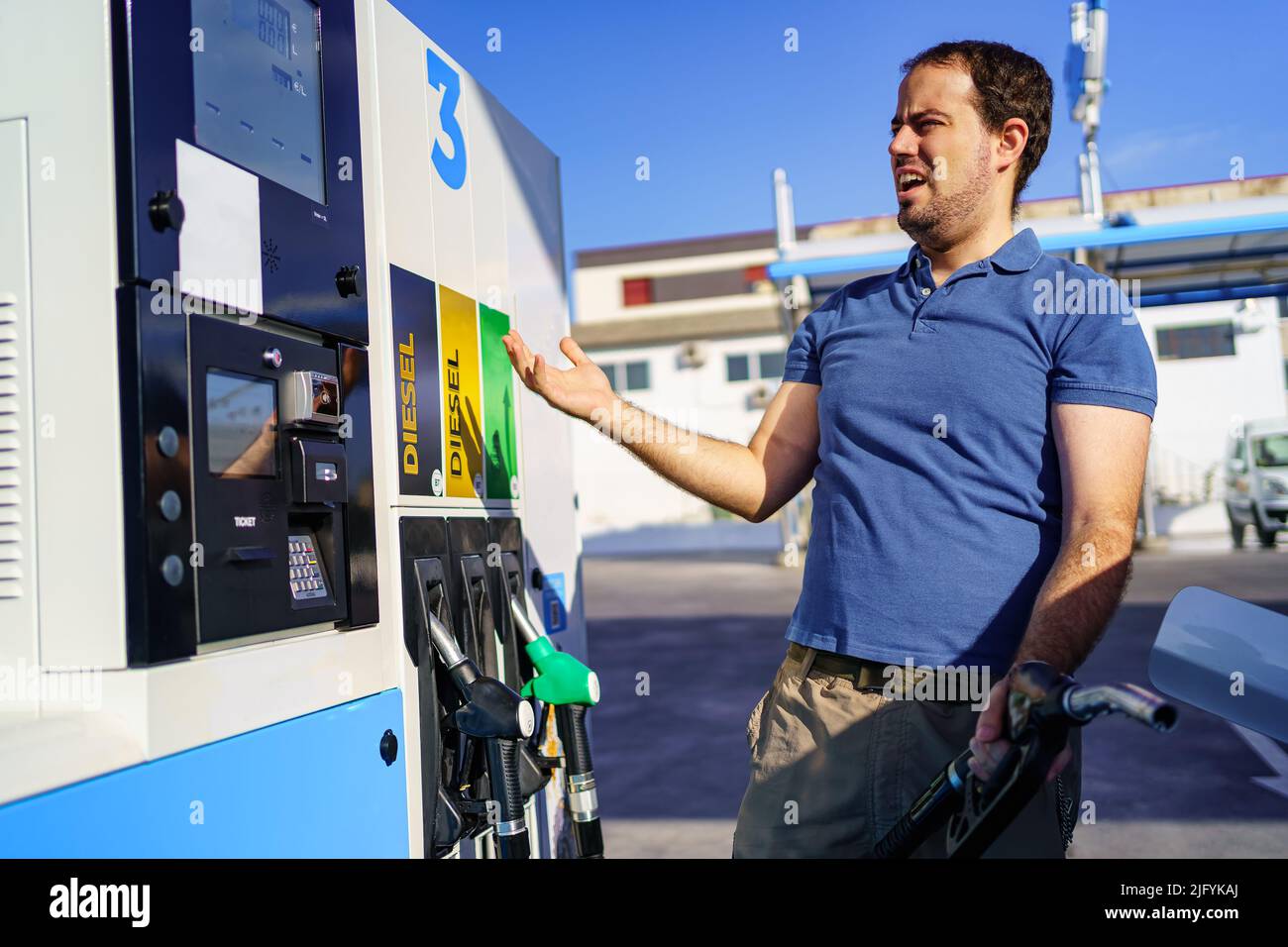 Mann überrascht von teuren Kraftstoffpreisen an einer Tankstelle. Stockfoto