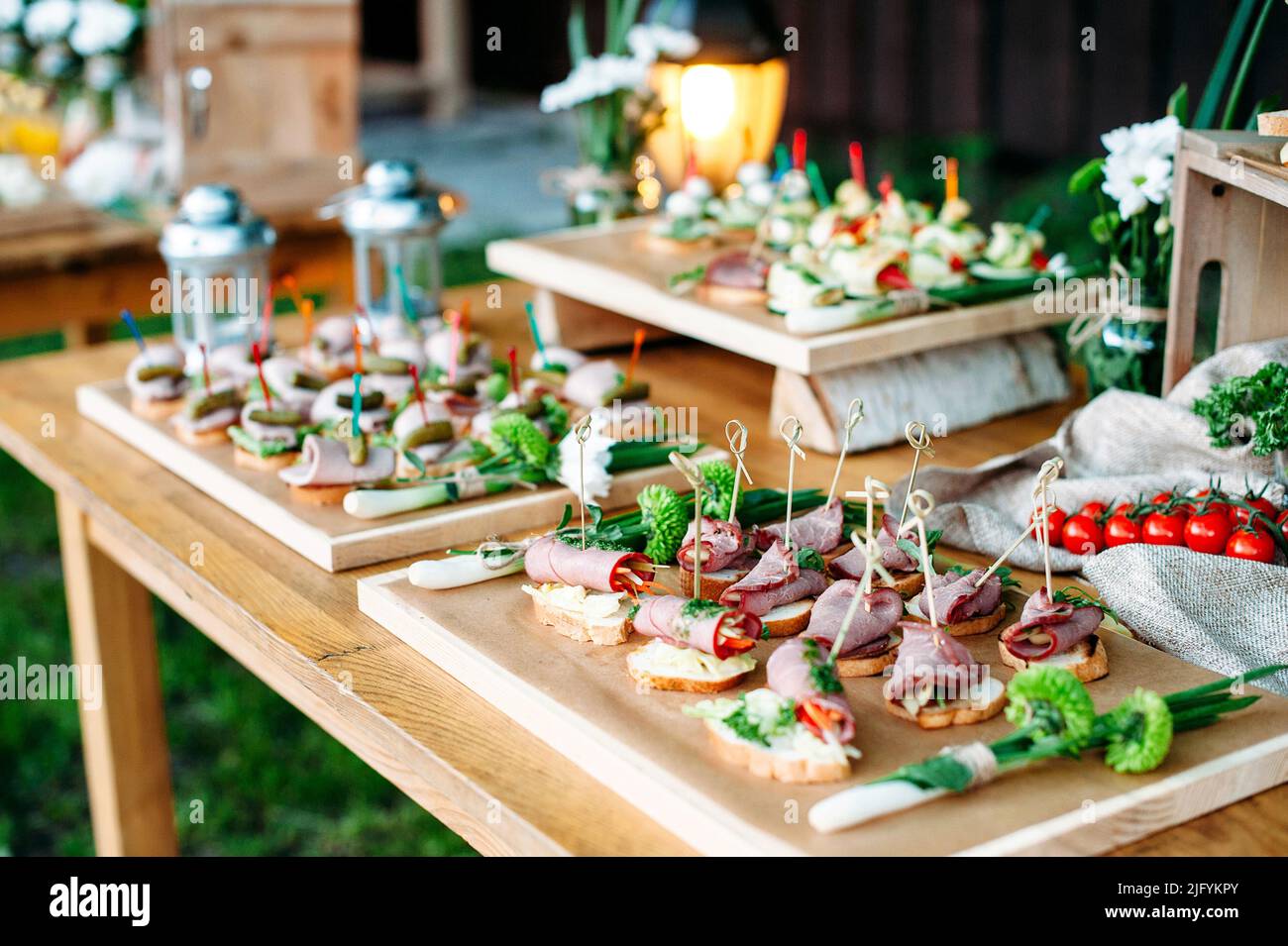 Schöner Catering-Bankett-Buffet-Tisch im rustikalen Stil im Garten dekoriert. Verschiedene Snacks, Sandwiches. Im Freien. Stockfoto