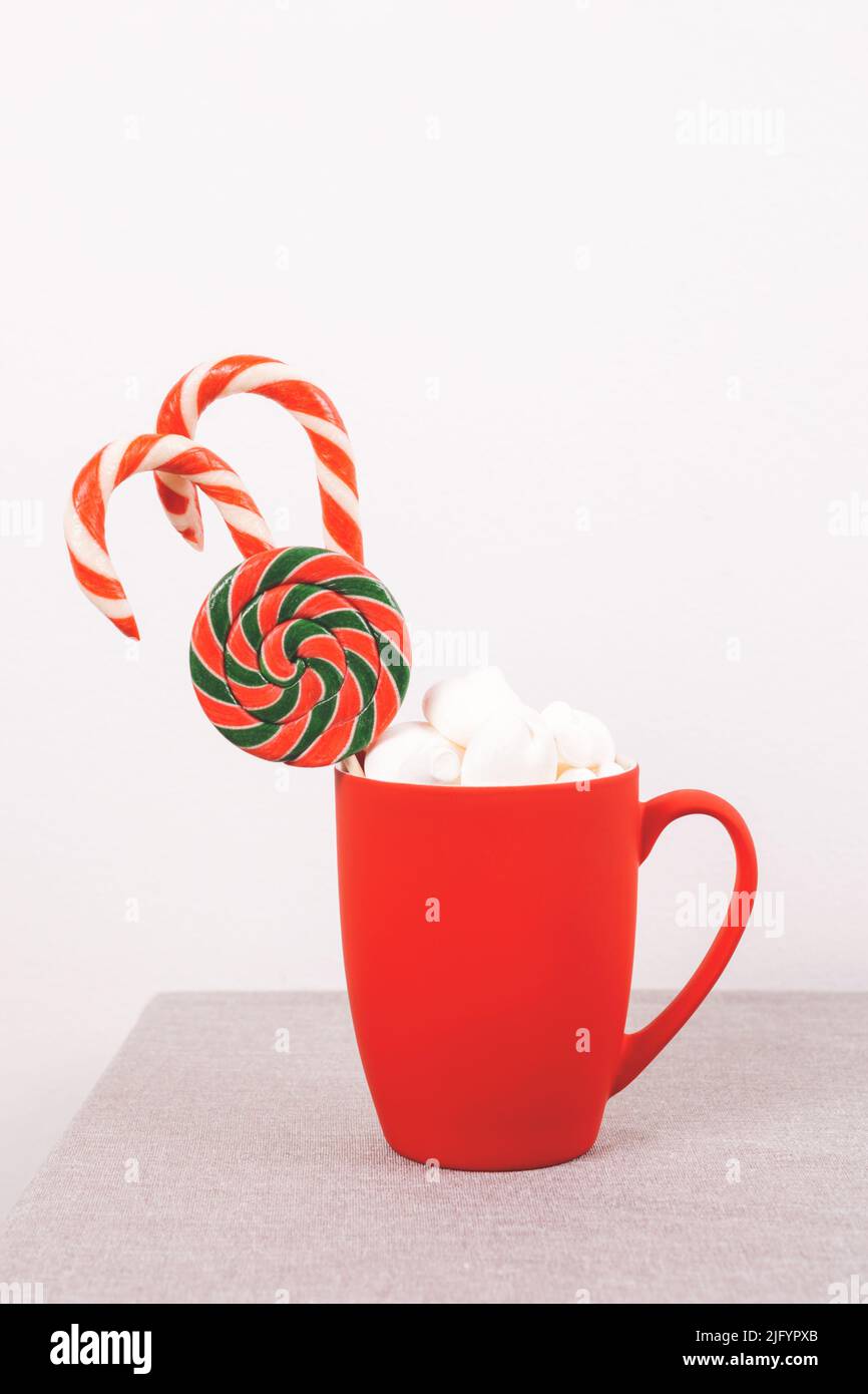 Weihnachtsgeschenke in rotem Becher an weißer Wand mit leerem Platz. Vorderansicht, Kopierbereich. Stockfoto