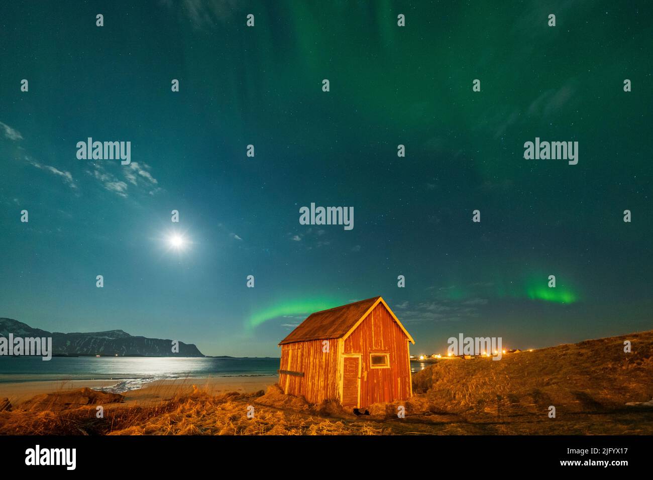 Rote Holzhütte am Sandstrand, der während der Nordlichter, Ramberg, Nordland County, Lofoten Islands, Norwegen, Skandinavien Stockfoto