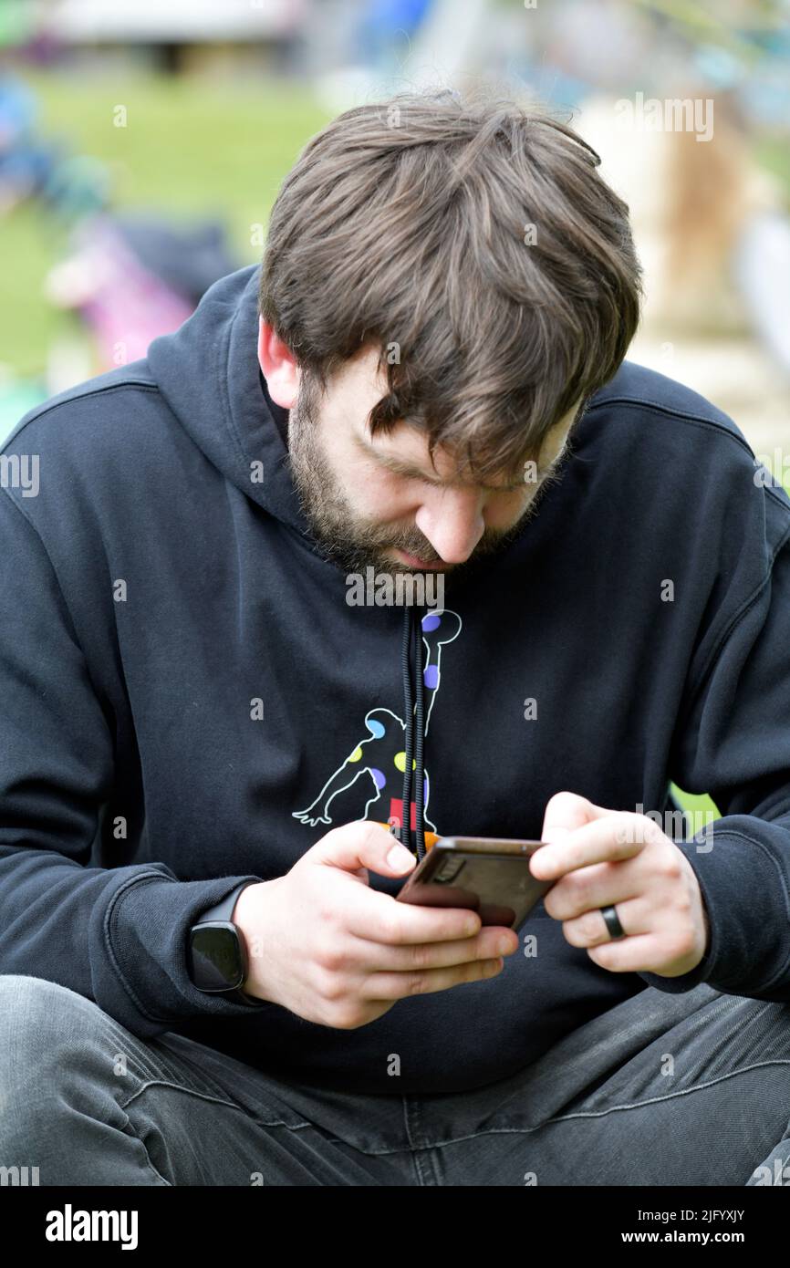 Junger Mann, der auf das Mobiltelefon schaut Stockfoto