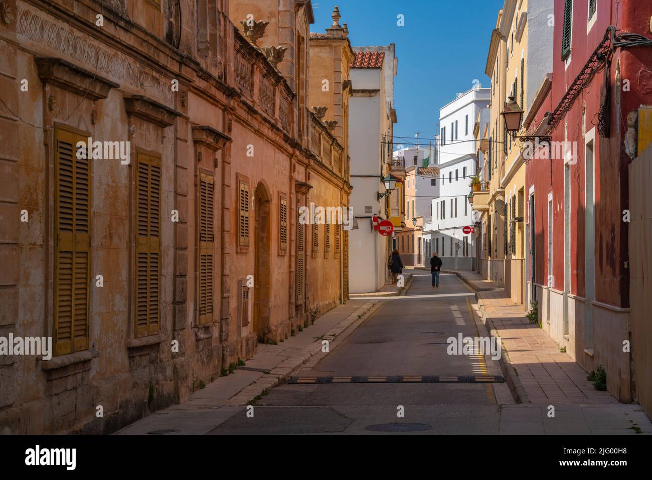 Blick auf ein Paar, das durch eine pastellfarbene Straße in der Altstadt geht, Ciutadella, Menorca, Balearen, Spanien, Mittelmeer, Europa Stockfoto