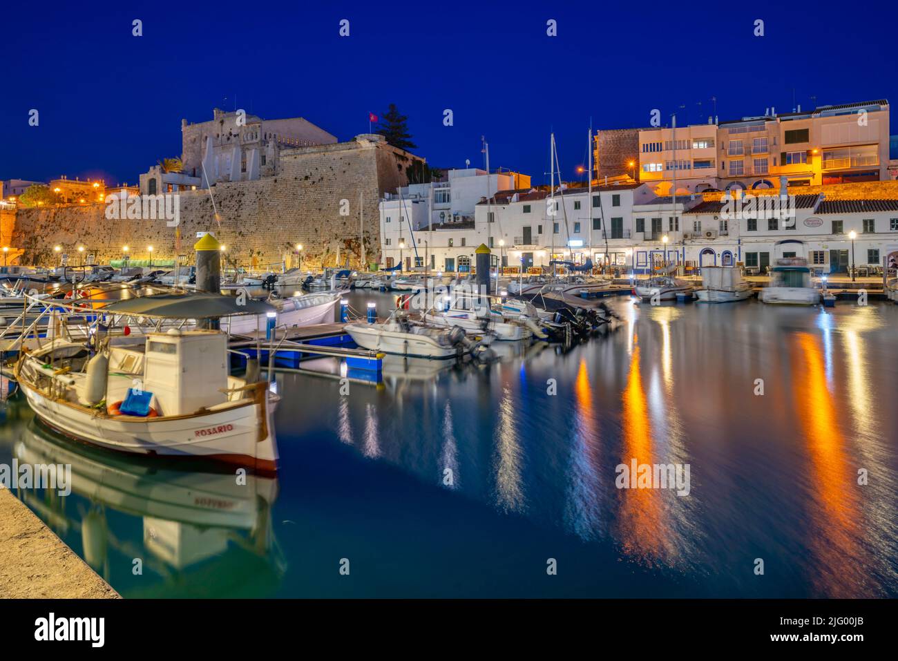 Blick auf Boote in der Marina, die in der Abenddämmerung von weiß getünchten Gebäuden überblickt werden, Ciutadella, Menorca, Balearen, Spanien, Mittelmeer, Europa Stockfoto