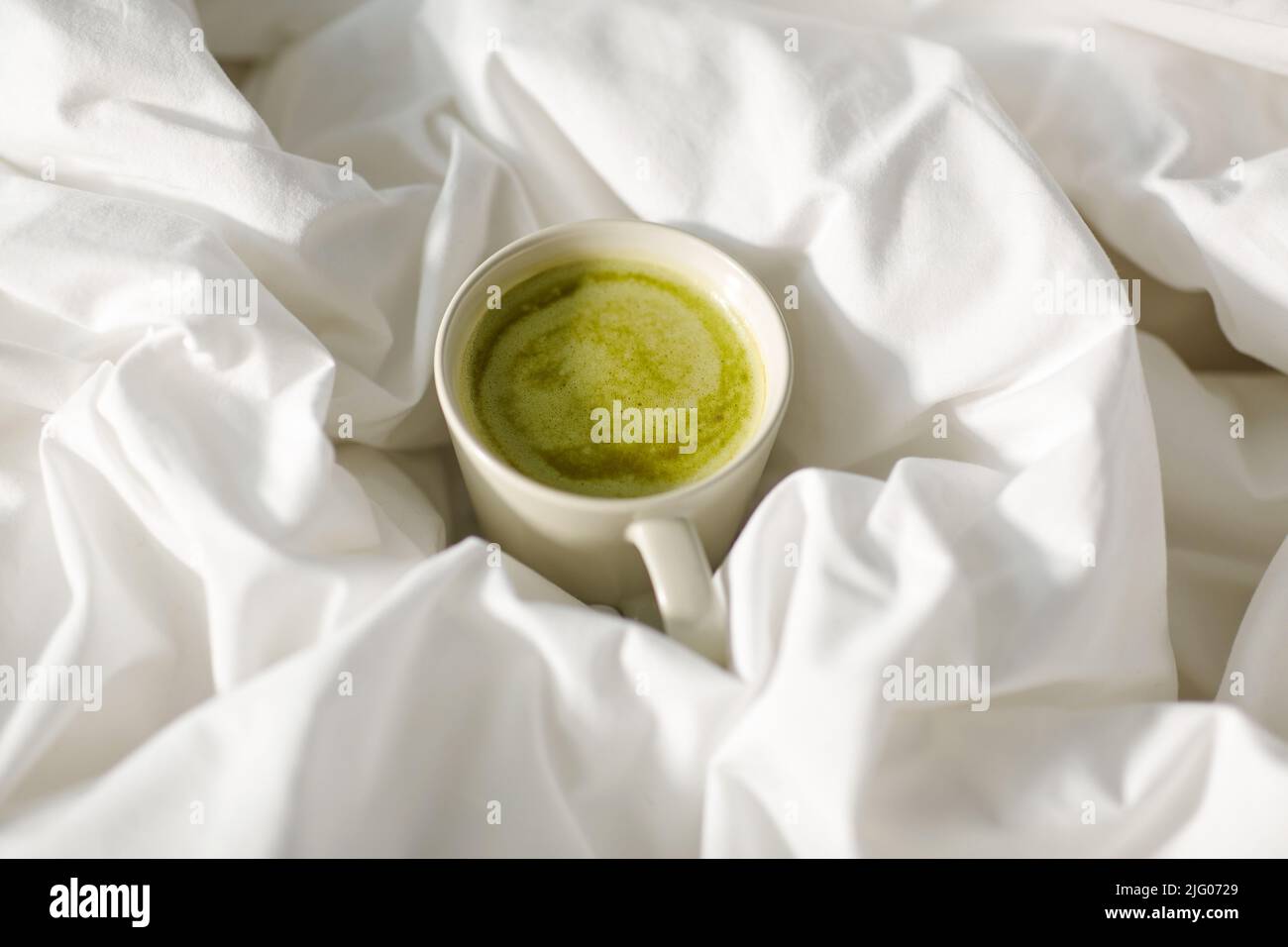 tasse Matcha-Tee im Bett zu Hause Stockfoto