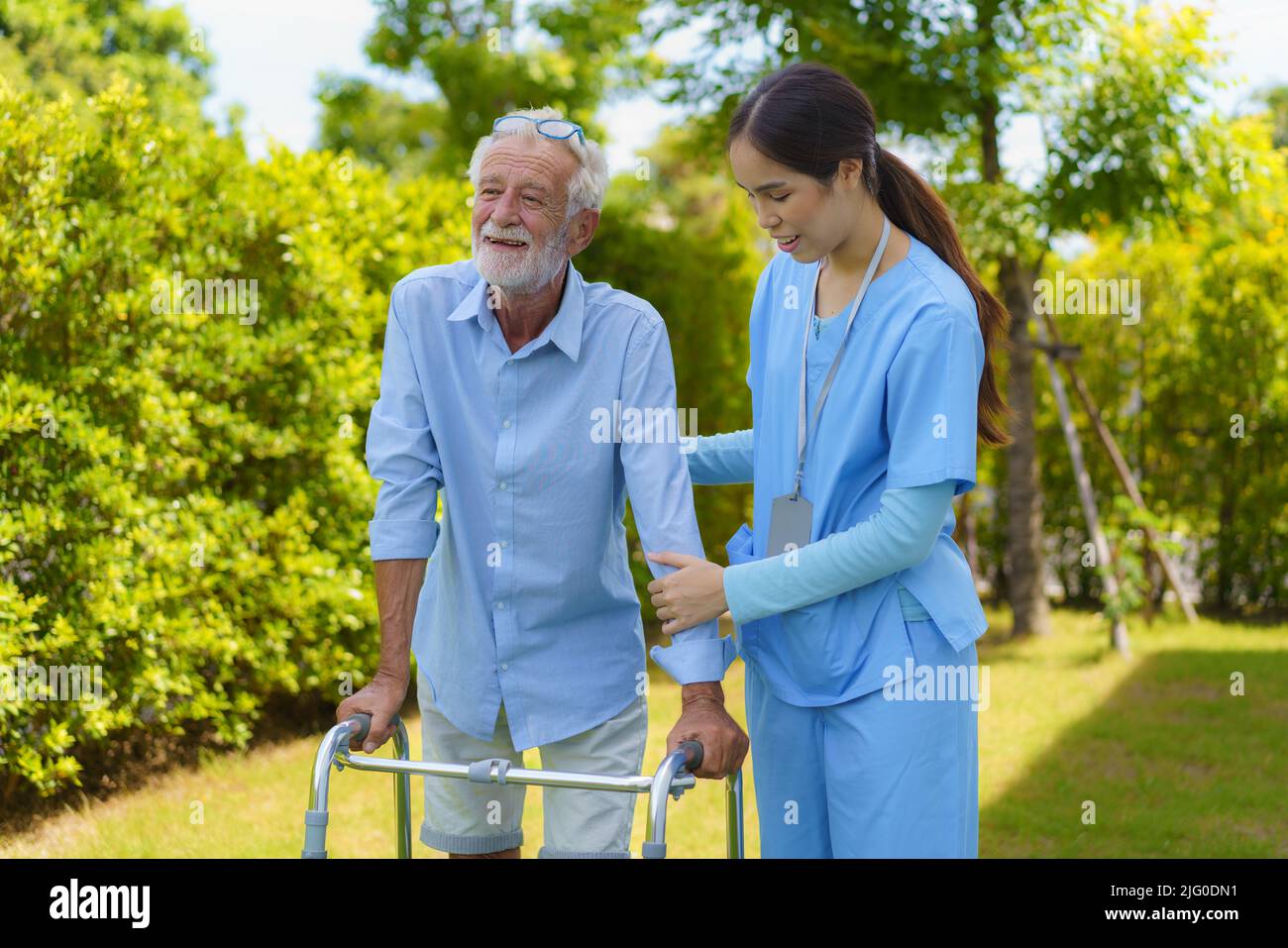 Junge asiatische Frau Krankenschwester Pflegerin hilft älteren Mann mit Mobilität Wanderer im Garten zu Hause. Seniorenkita, Krankenschwester kümmern ältere Patie Stockfoto