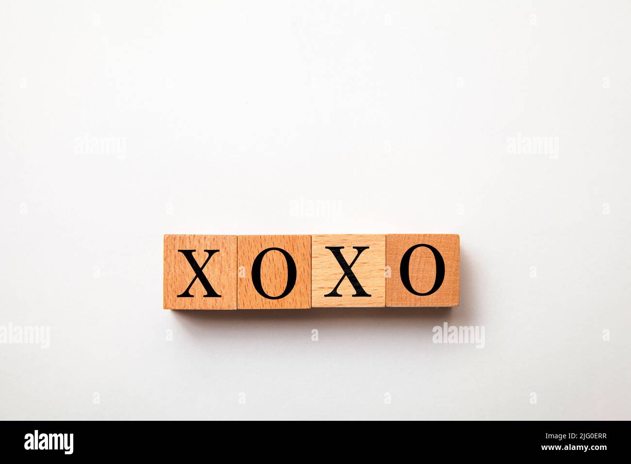 Der Charakter von Xoxo. Umarmungen und Küsse. Ausdruck der Zuneigung. Geschrieben auf vier Holzblöcken. Schwarze Buchstaben. Weißer Hintergrund. Stockfoto