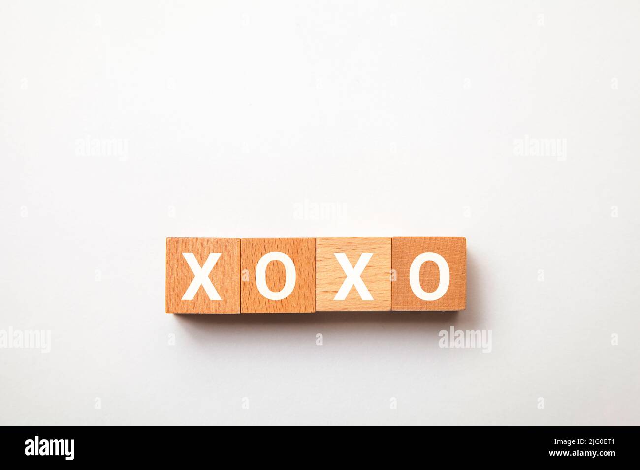 Der Charakter von Xoxo. Umarmungen und Küsse. Ausdruck der Zuneigung. Geschrieben auf vier Holzblöcken. Weiße Buchstaben. Weißer Hintergrund. Stockfoto
