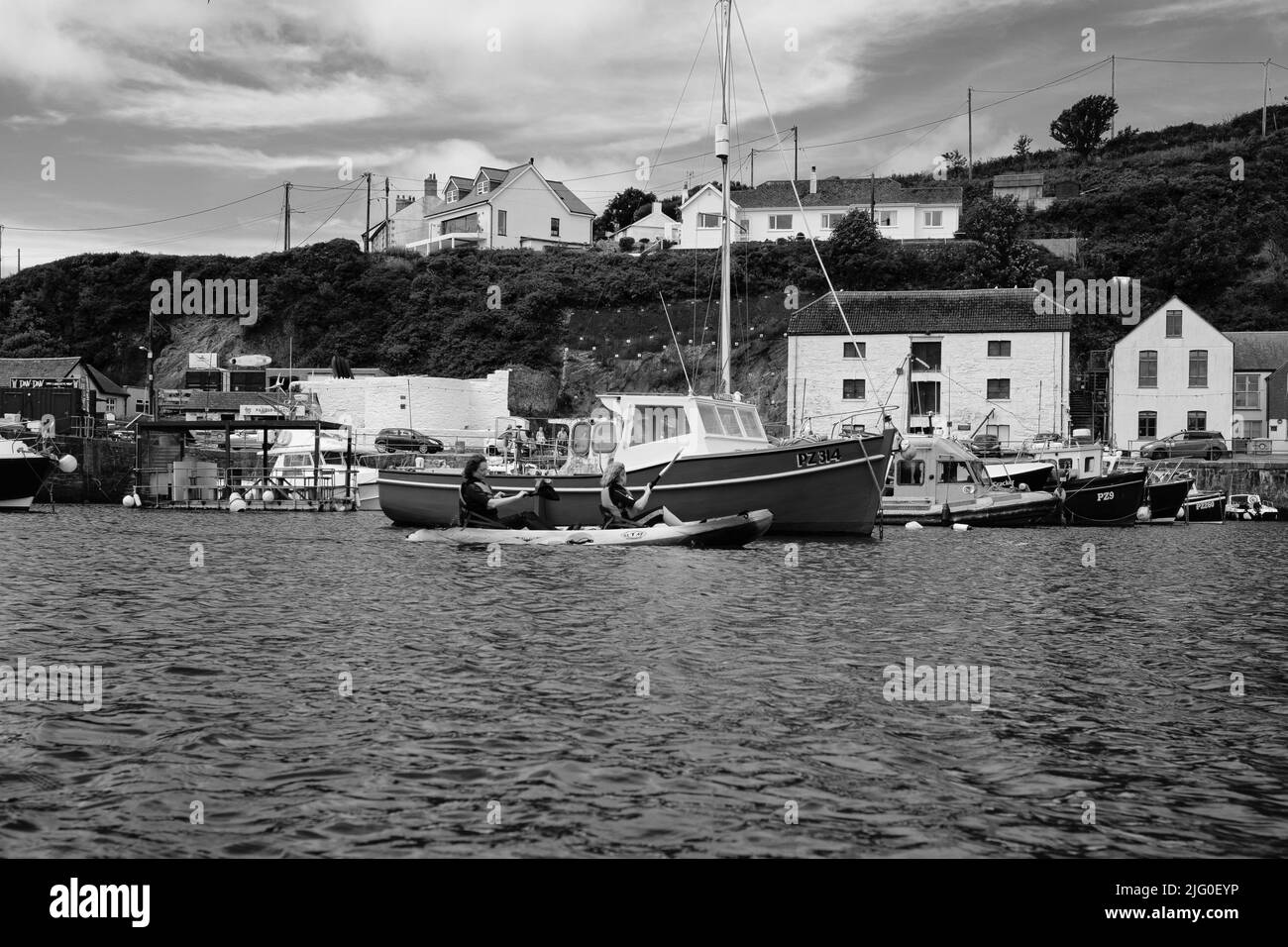 Touristen, die im Innenhafen von Porthleven, Cornwall, Kajakfahren Stockfoto