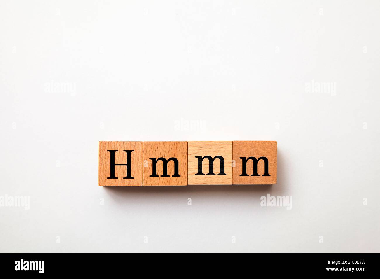 Hmm-Buchstaben. Hmmm. Denken Sie darüber nach. Geschrieben auf drei Holzblöcken. Schwarze Buchstaben. Weißer Hintergrund. Stockfoto