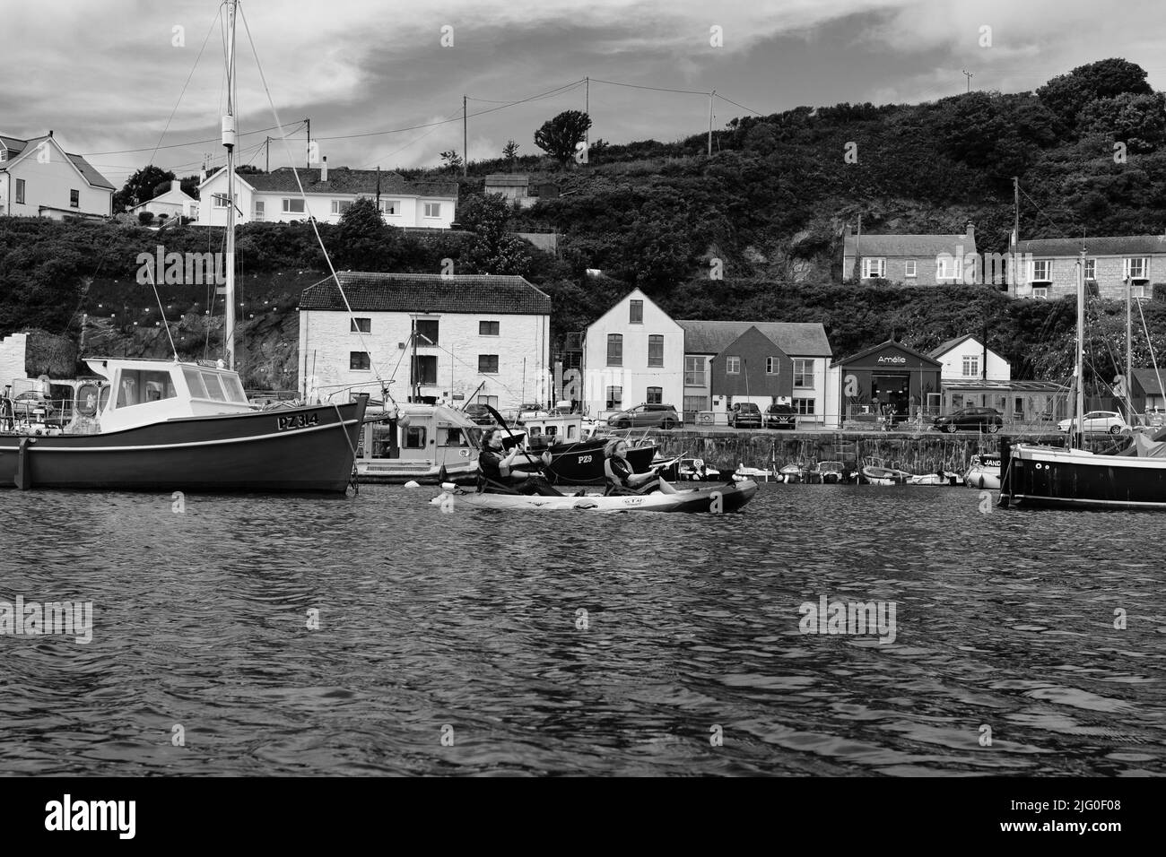 Touristen, die im Innenhafen von Porthleven, Cornwall, Kajakfahren Stockfoto