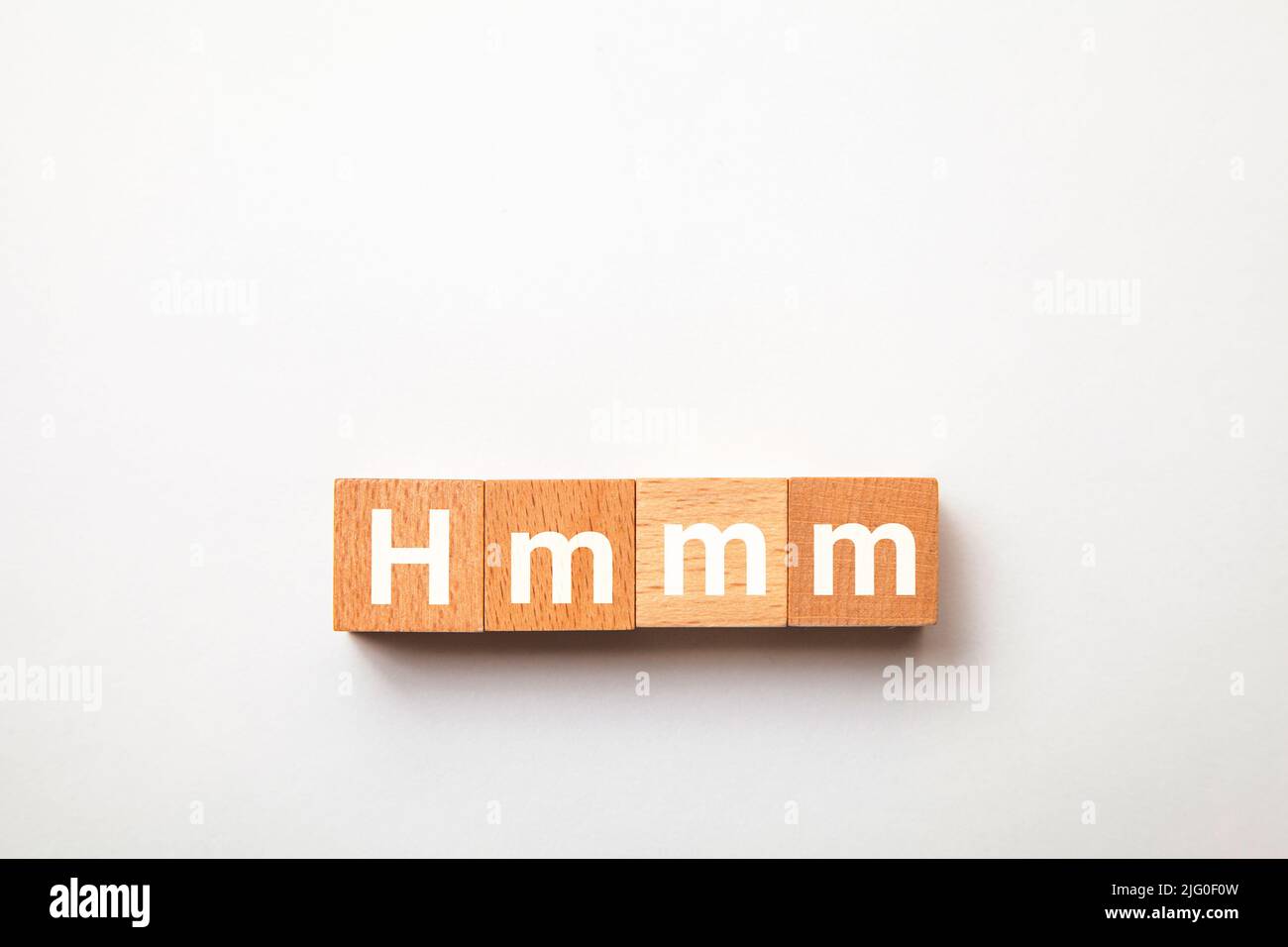 Hmm-Buchstaben. Hmmm. Denken Sie darüber nach. Geschrieben auf drei Holzblöcken. Weiße Buchstaben. Weißer Hintergrund. Stockfoto