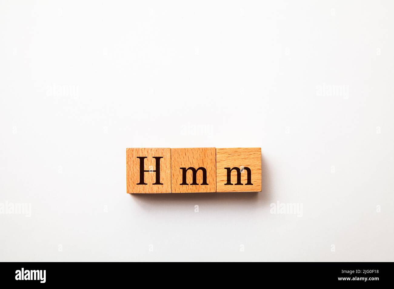 Hmm-Buchstaben. Hmmm. Denken Sie darüber nach. Geschrieben auf drei Holzblöcken. Schwarze Buchstaben. Weißer Hintergrund. Stockfoto