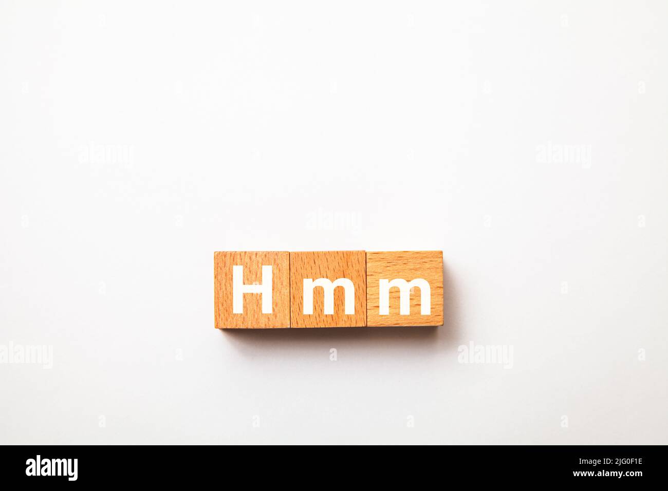 Hmm-Buchstaben. Hmmm. Denken Sie darüber nach. Geschrieben auf drei Holzblöcken. Weiße Buchstaben. Weißer Hintergrund. Stockfoto