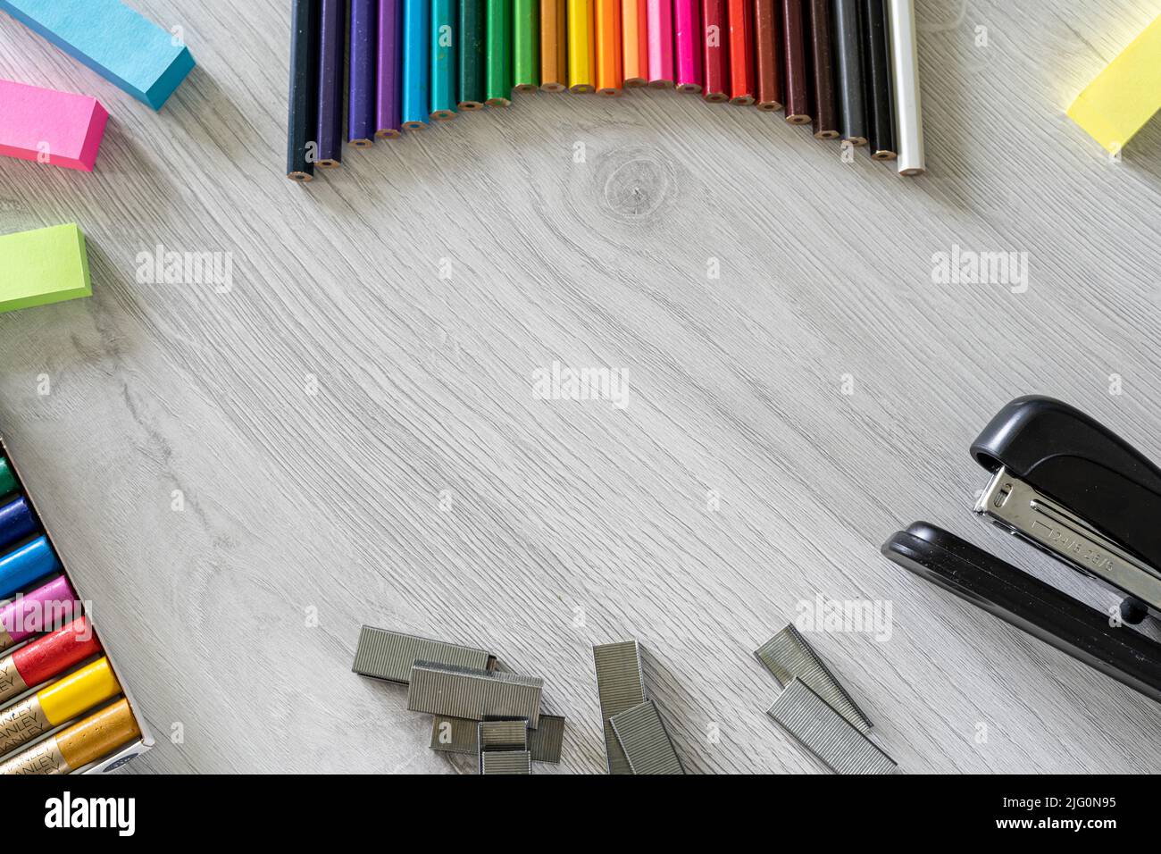 Ein Tisch voller farbiger Schulstifte, die einen Regenbogen bilden, und Vorräte für Schulkinder Stockfoto