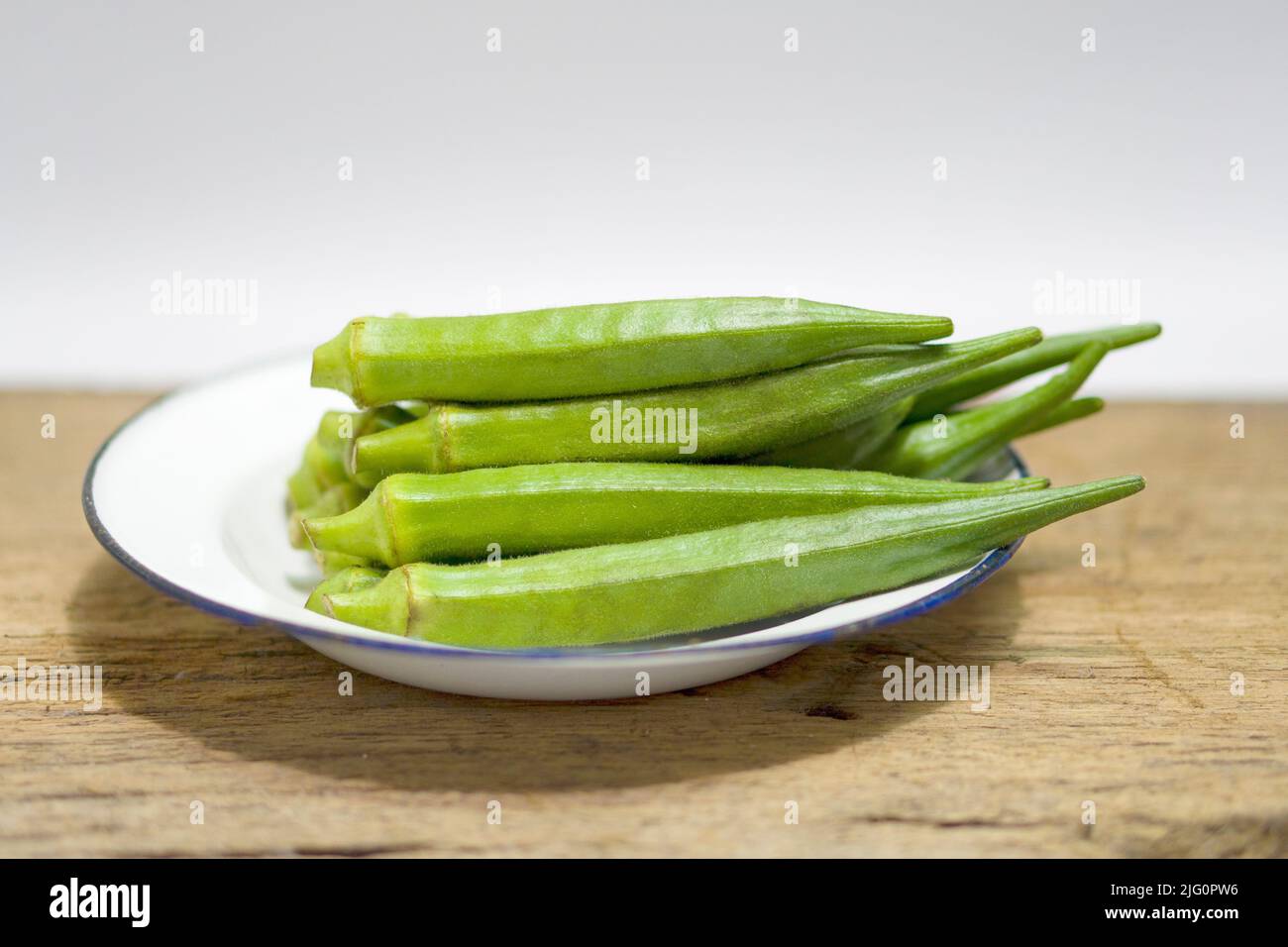 Stapel von frischen Okra auf Holzhintergrund, Gartenarbeit Bio grüne Obst sterben Gemüse Stockfoto