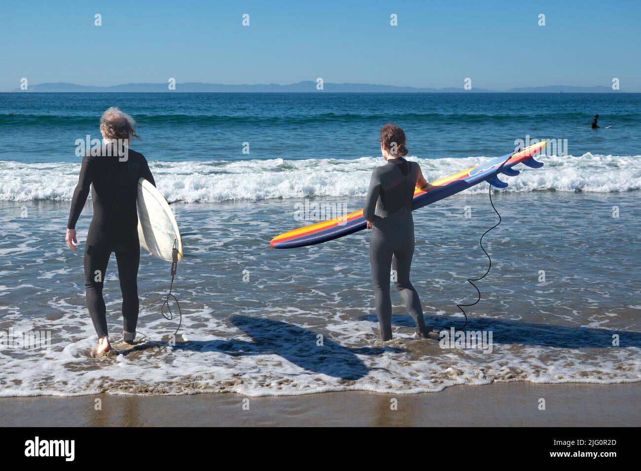 Rücken von zwei älteren Surfern, die Bretter in das Meer von Newport Beach im Süden Kaliforniens, USA, trugen Stockfoto