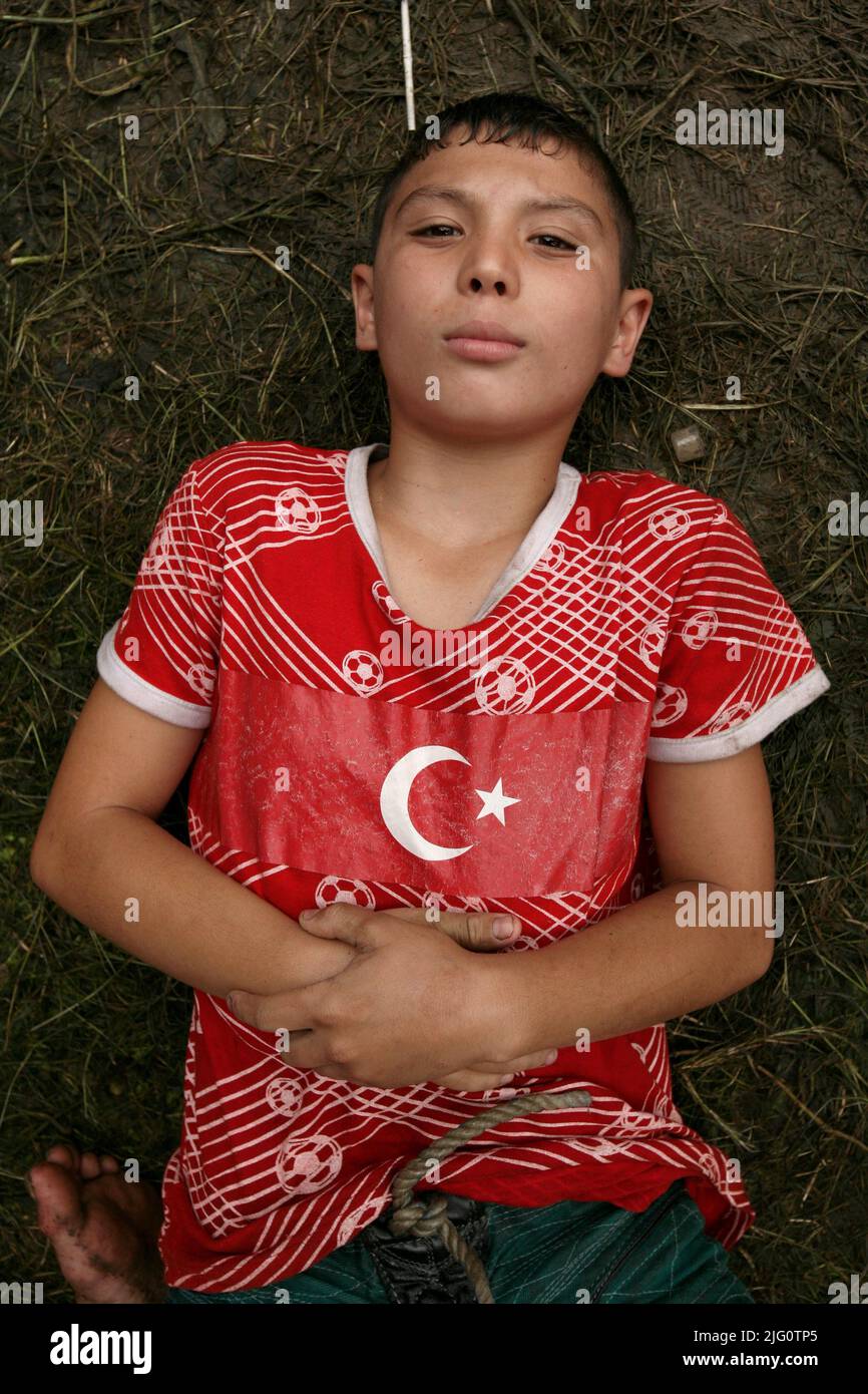 Kırkpınar (Türkisches Ölwrestling). Der junge, in einem roten T-Shirt gekleidete Ringer mit einer türkischen Nationalflagge liegt auf dem Boden und wartet auf seinen Kampf während des Kırkpınar-Turniers 648. in Edirne, Türkei, am 4. Juli 2009. Stockfoto