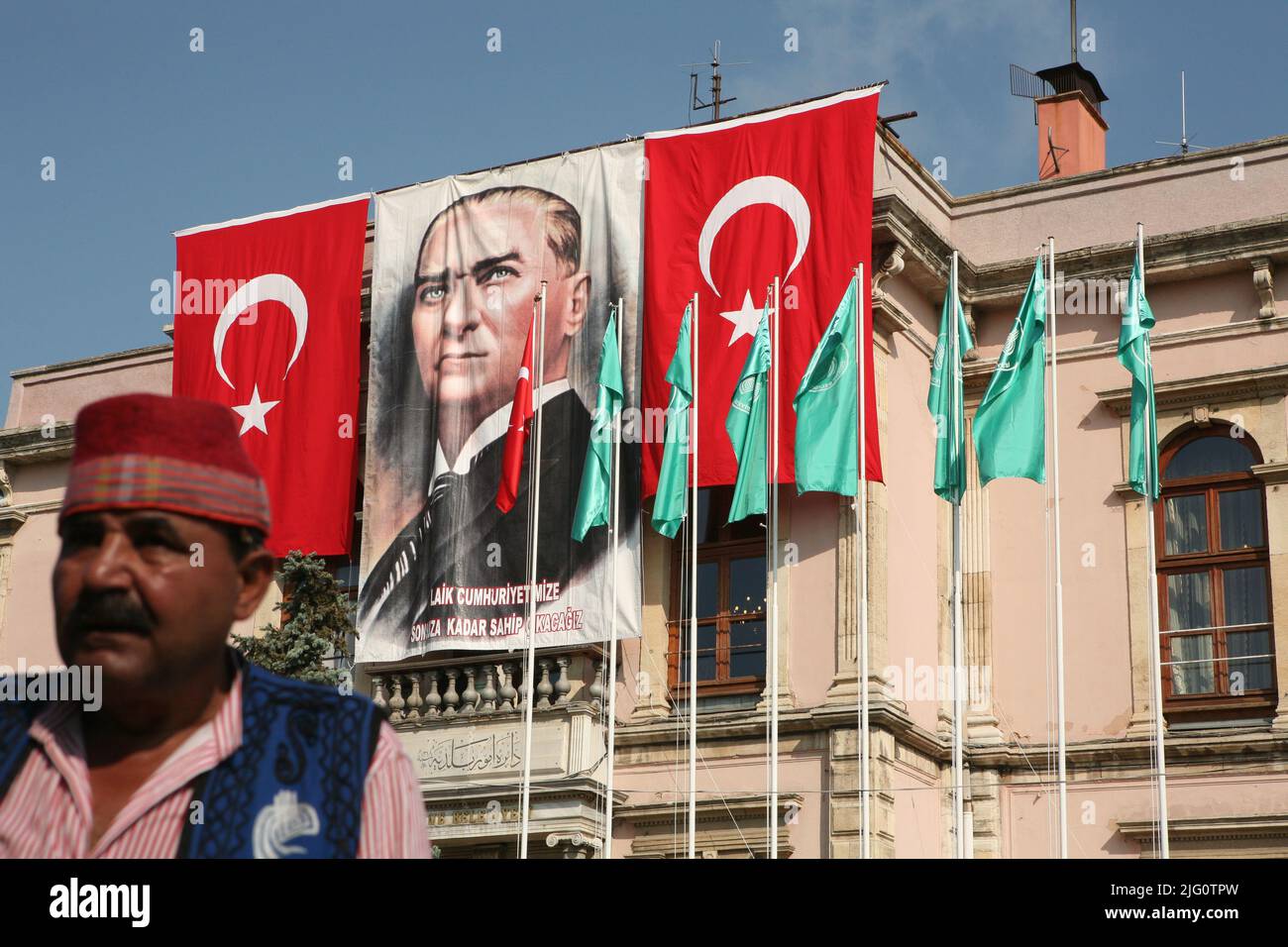 Kırkpınar (Türkisches Ölwrestling). Turniermusiker, der vor dem riesigen Porträt von Mustafa Kemal Atatürk abgebildet ist, das mit türkischen Nationalflaggen auf dem Gebäude des Rathauses von Edirne während der Eröffnungsfeier des Kırkpınar-Turniers 648. in Edirne, Türkei, am 3. Juli 2009 geschmückt ist. Stockfoto
