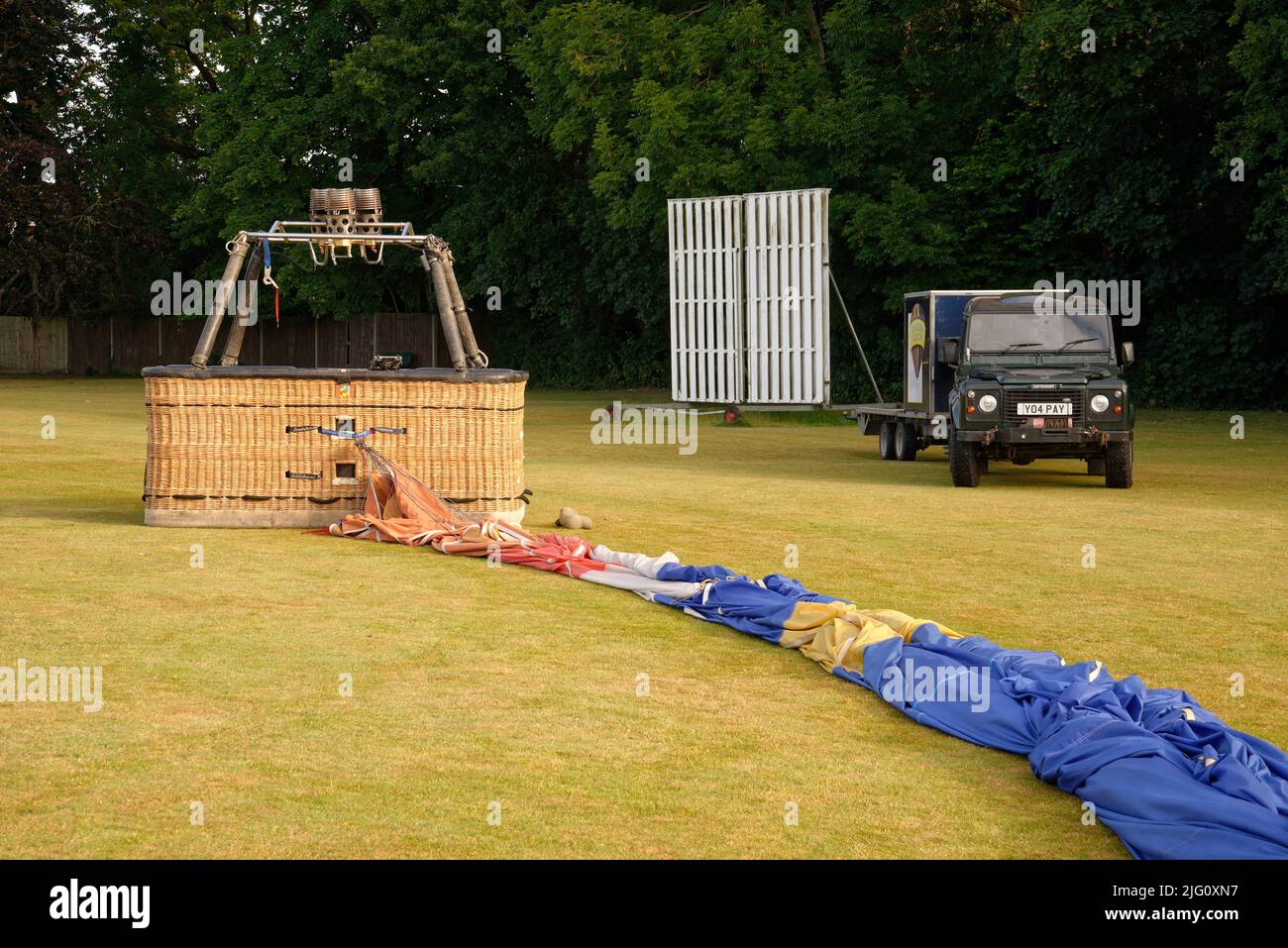 Ein Heißluftballon. Den Ballon nach der Landung in der Nähe eines Cricket-Platzes weglegen. Die Gondel (Korb) und der gefaltete Umschlag (Ballonstoff). Stockfoto