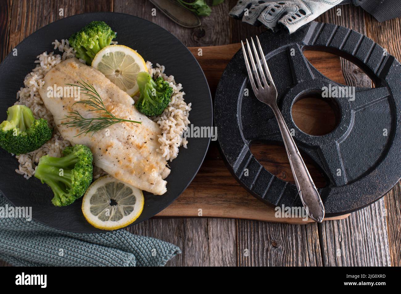 Fitness-Dinner mit Fisch, braunem Reis und Brokkoli auf einem Teller Stockfoto