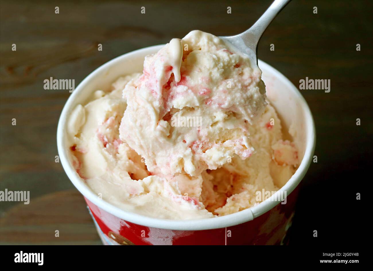 Nahaufnahme eines Löffels, der köstliche cremige Erdbeer-Käsekuchen-Eiscreme ausschaufelt Stockfoto