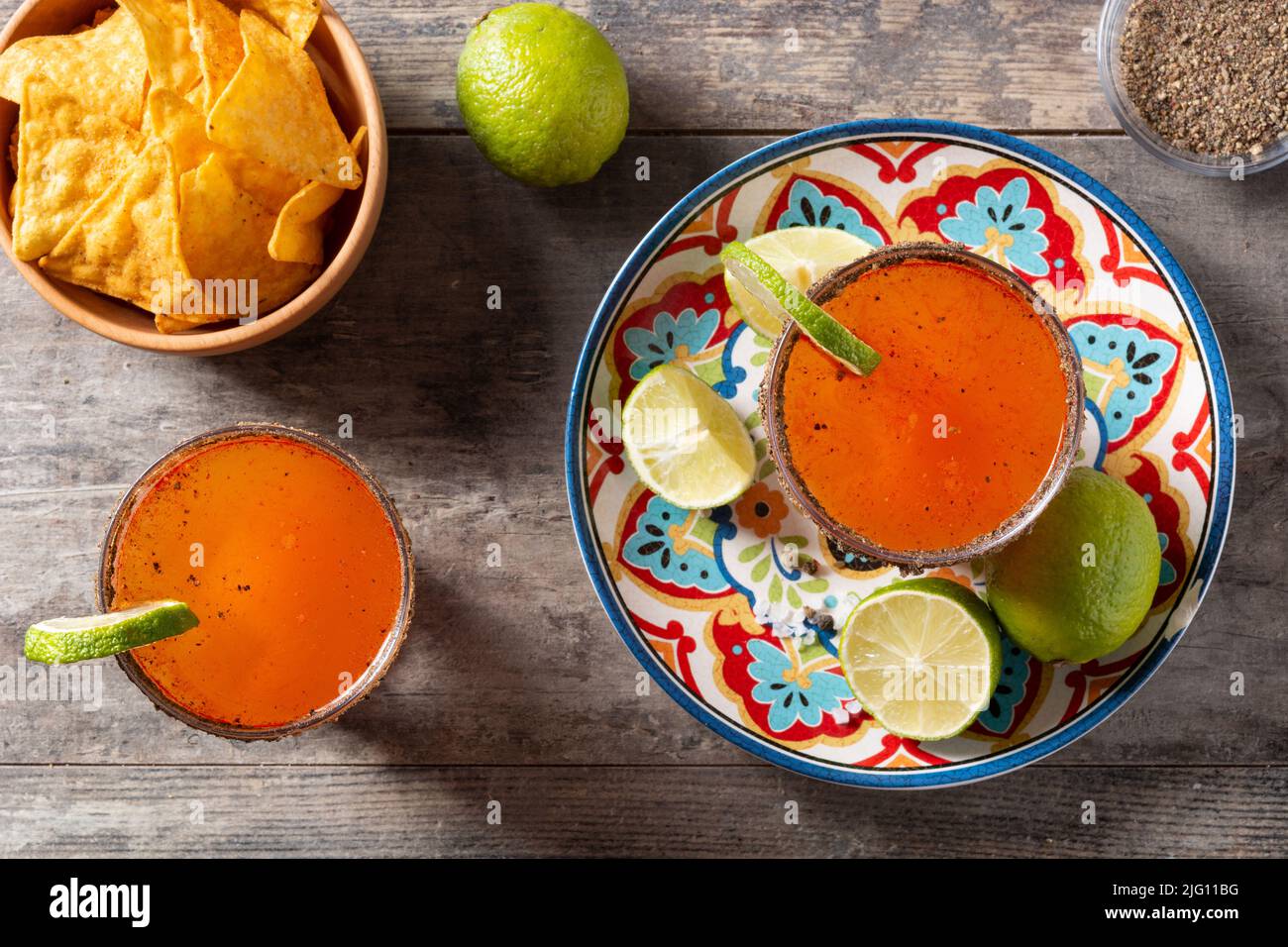 Hausgemachter Michelada-Cocktail mit Bier, Limettensaft, heißer Sauce, gesalzenem Rand und Tomatensaft auf dem Holztisch Stockfoto