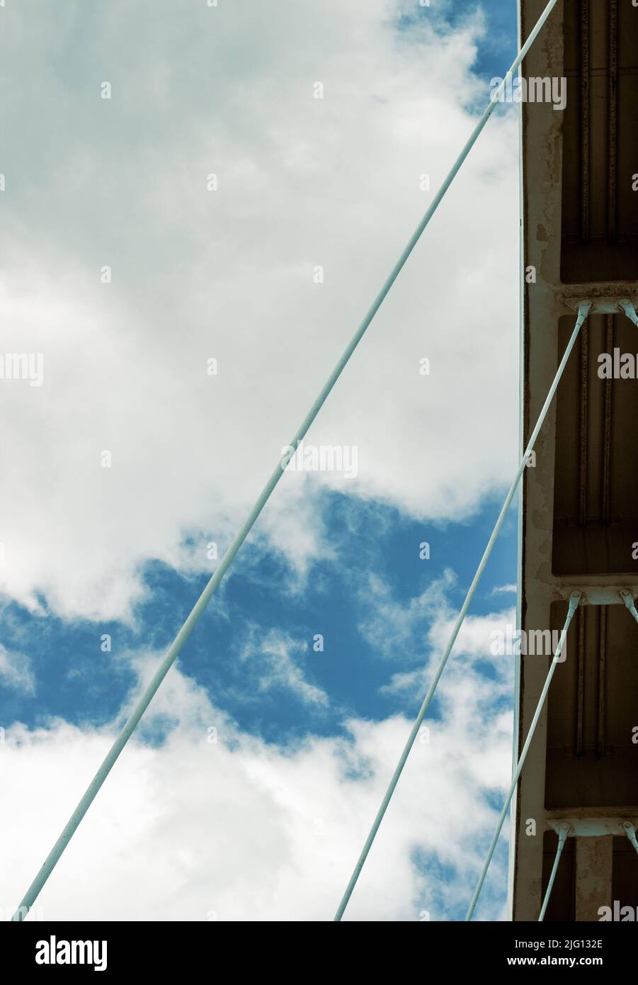 Ein Winkel, der auf einen Abschnitt einer Fußgängerbrücke gegen einen wolkigen, blauen Himmel blickt. Stockfoto
