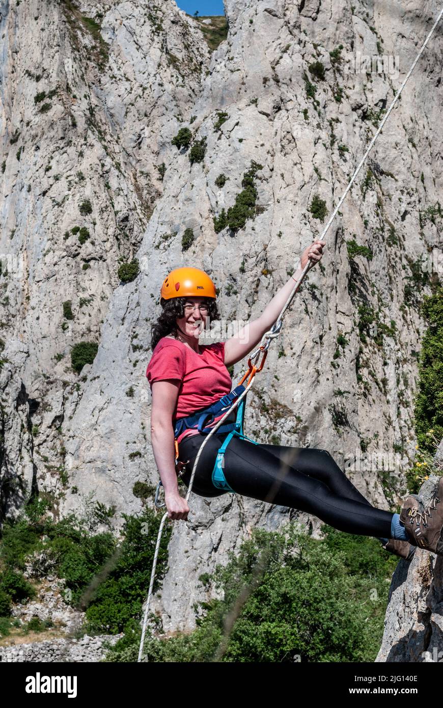 Schöne Frau klettert auf hohen Felsen bei Sonnenuntergang Nebel in den Bergen. Konzept von Abenteuer und Extremsport Stockfoto