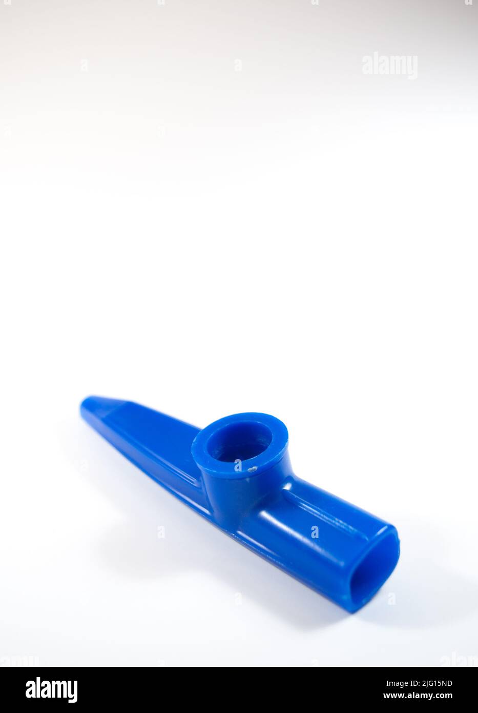 Blauer Kazoo, Kazoo ist ein Blasinstrument. Isoliert auf weißem Hintergrund. Platz kopieren, Platz für Text. Draufsicht. Keine Menschen, niemand. Vertikales Foto. Stockfoto