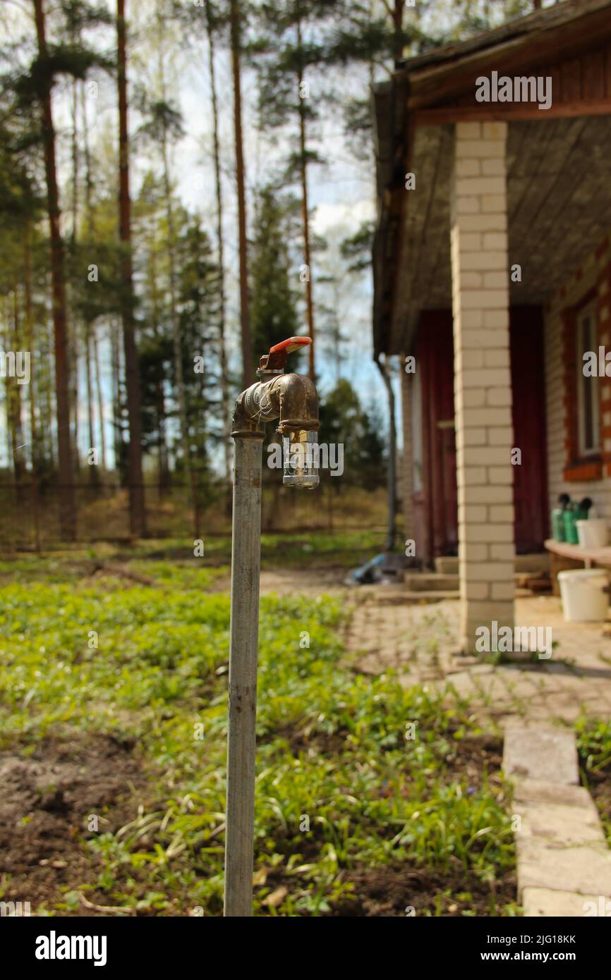 Ein alter rostiger Wasserhahn in einem Garten. Gartenhahn im Sommerhaus. Stockfoto