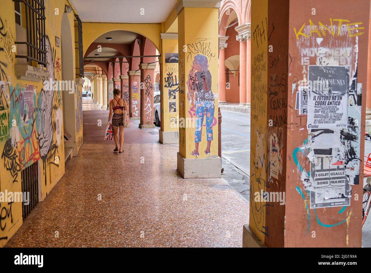 Junge Studenten spazieren unter den Lauben von Graffiti-überdachten Arkaden im Universitätsbezirk in Bologna Italien Stockfoto