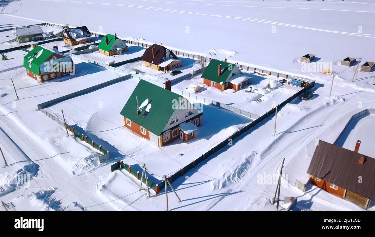 Blick von oben auf schöne Hütten mit weißem Schnee. Clip. Landhäuser mit klarem Feld am Wintertag. Cottage Village am sonnigen Wintertag. Stockfoto