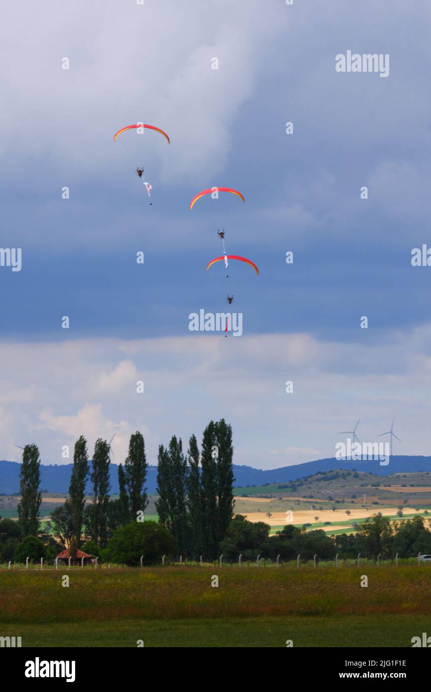 Drei Fallschirmspringer am bewölkten Himmel ziehen Flagge, Banner und Poster von Atatürk für eine Airshow in der Türkei Stockfoto