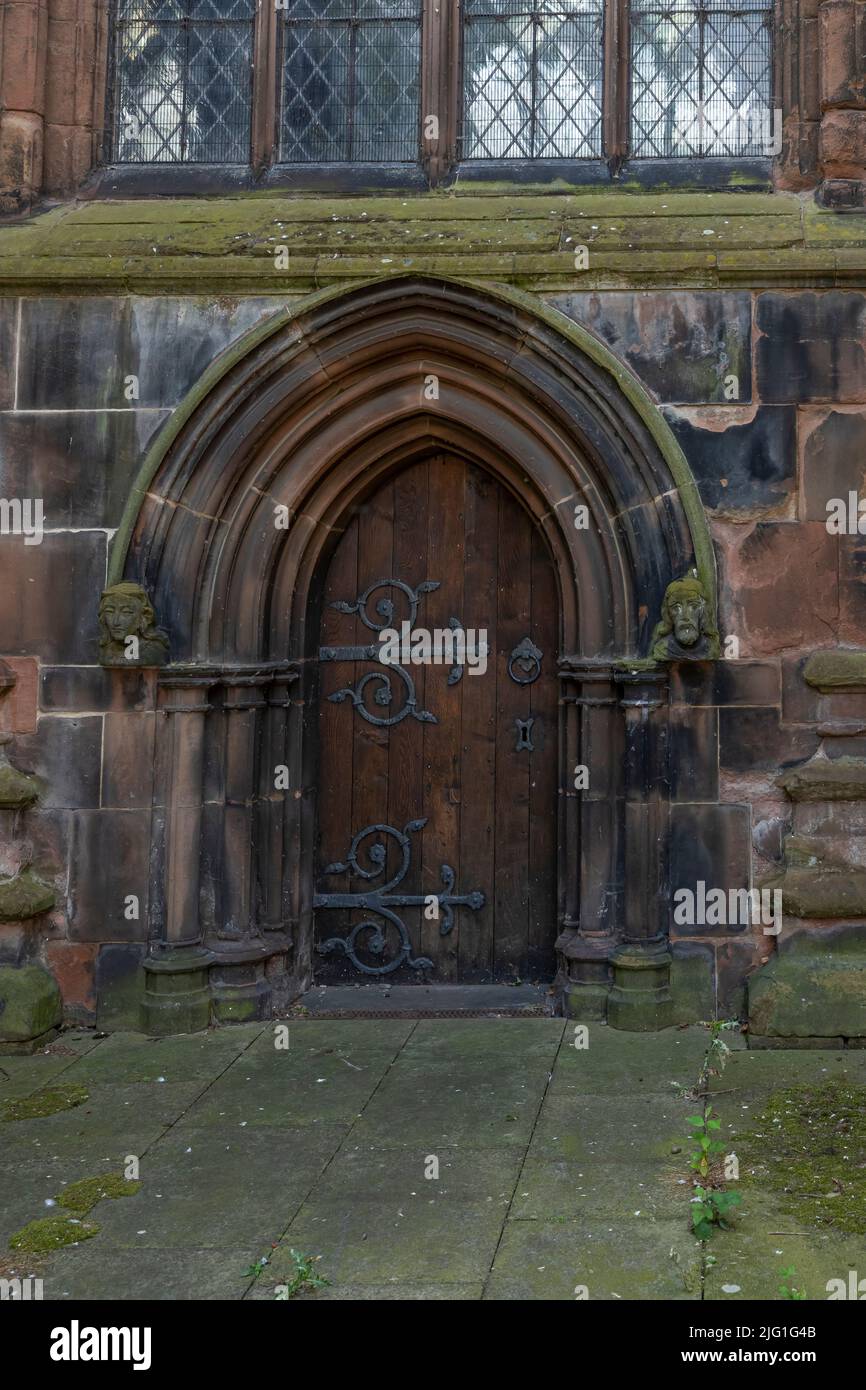 Alte Holztür auf einer Kirche mit verzierten Scharnieren, Schloss und rundem Griff Stockfoto