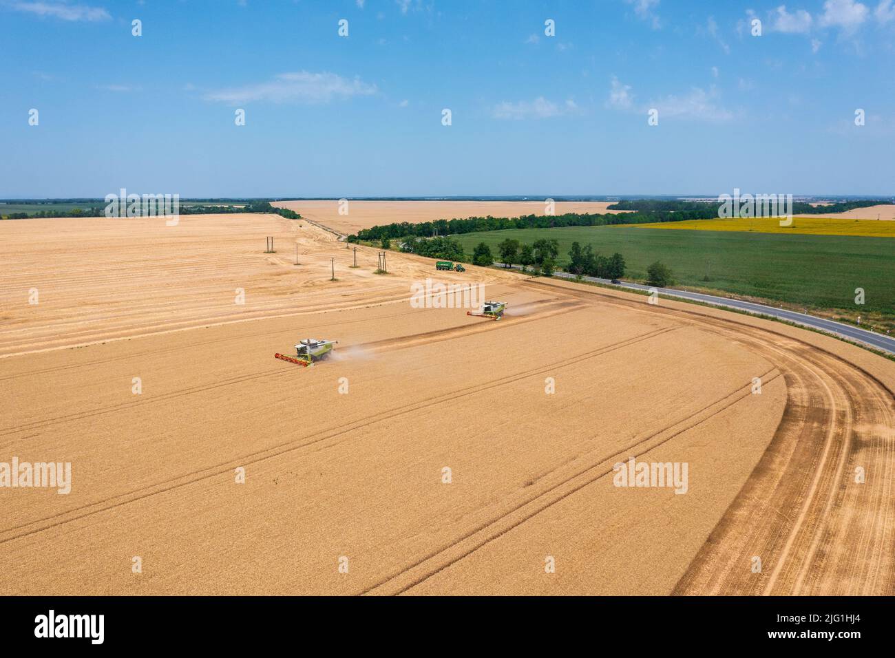 Luftaufnahme über Mähdrescher, die auf Weizenfeld arbeiten. Agrargeschäft, ungarische Agrarlandschaft, Lebensmittelkrise. Stockfoto
