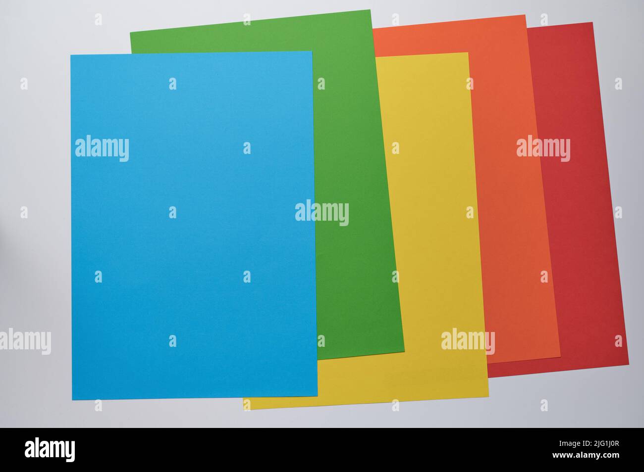 Fünf Blatt Papier in blau, grün, gelb, orange und rot übereinander liegend, Kopierraum Stockfoto