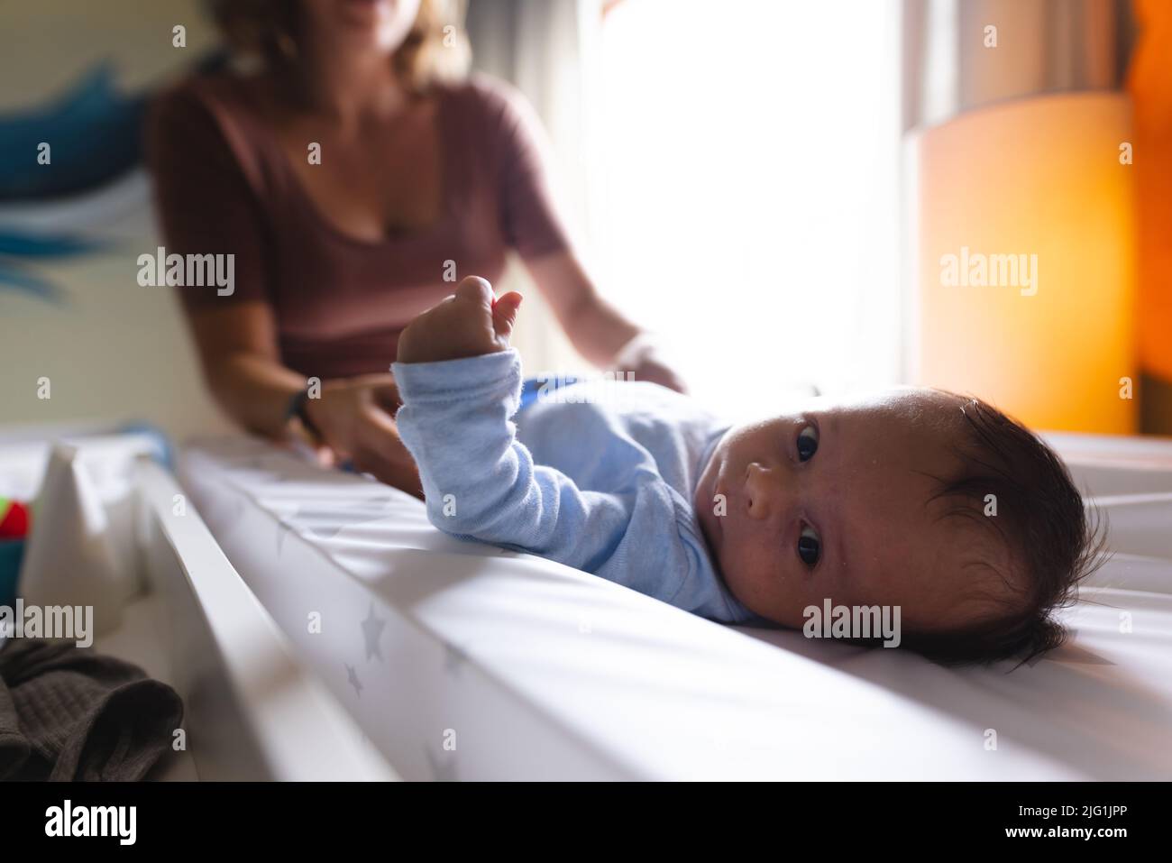 Porträt von niedlichen Neugeborenen, das von der kaukasischen Mutter zu Hause auf einem Wickeltisch liegt Stockfoto