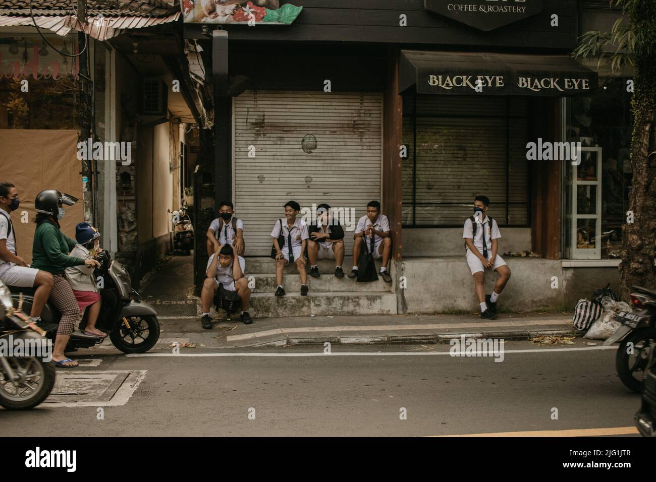 Balinesische Schüler, die nach der Schule auf der Straße sitzen Stockfoto