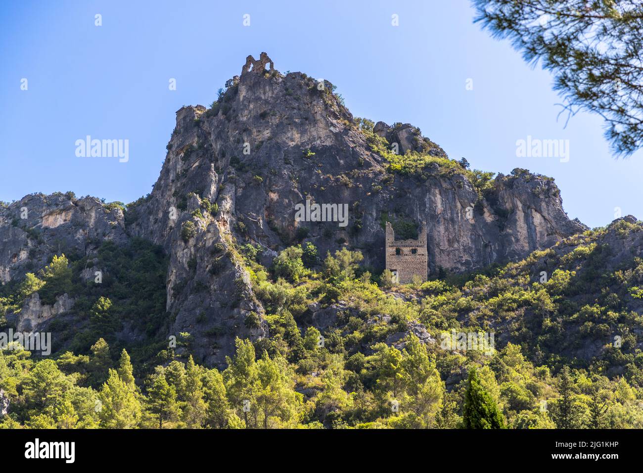 Die Ruinen des Château du Géant krönen einen schroffen Felsgipfel über Saint-Guilhem-le-Désert, Hérault. König Ludwig von Aquitanien gewährte die Burg 807 an Guilhem, Gründer der nahe gelegenen Abtei von Gellone; die erhaltenen Mauern stammen wahrscheinlich aus dem 12. Jahrhundert. Stabilisierungsarbeiten an der bröckelnden Ruine begannen im Jahr 2022. Das Dorf liegt an der Via Tolosana, der Arles-Route des Jakobsweges, ist in der Liste der „Plus Beaux Villages de France“ aufgeführt und seit 1998 Teil des UNESCO-Weltkulturerbes. Stockfoto