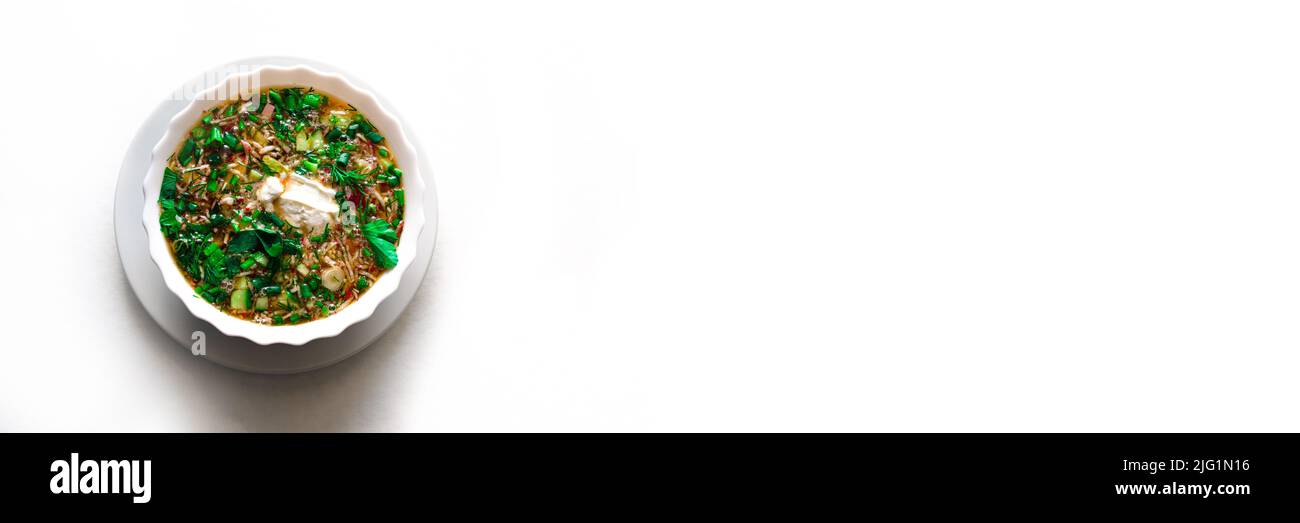 Sommer kalte Suppe - okroshka in einer weißen Keramikschale. Auf einem isolierten weißen Hintergrund. Zutaten: Kartoffeln, Radieschen, Gurken, Petersilie, Eier. Stockfoto
