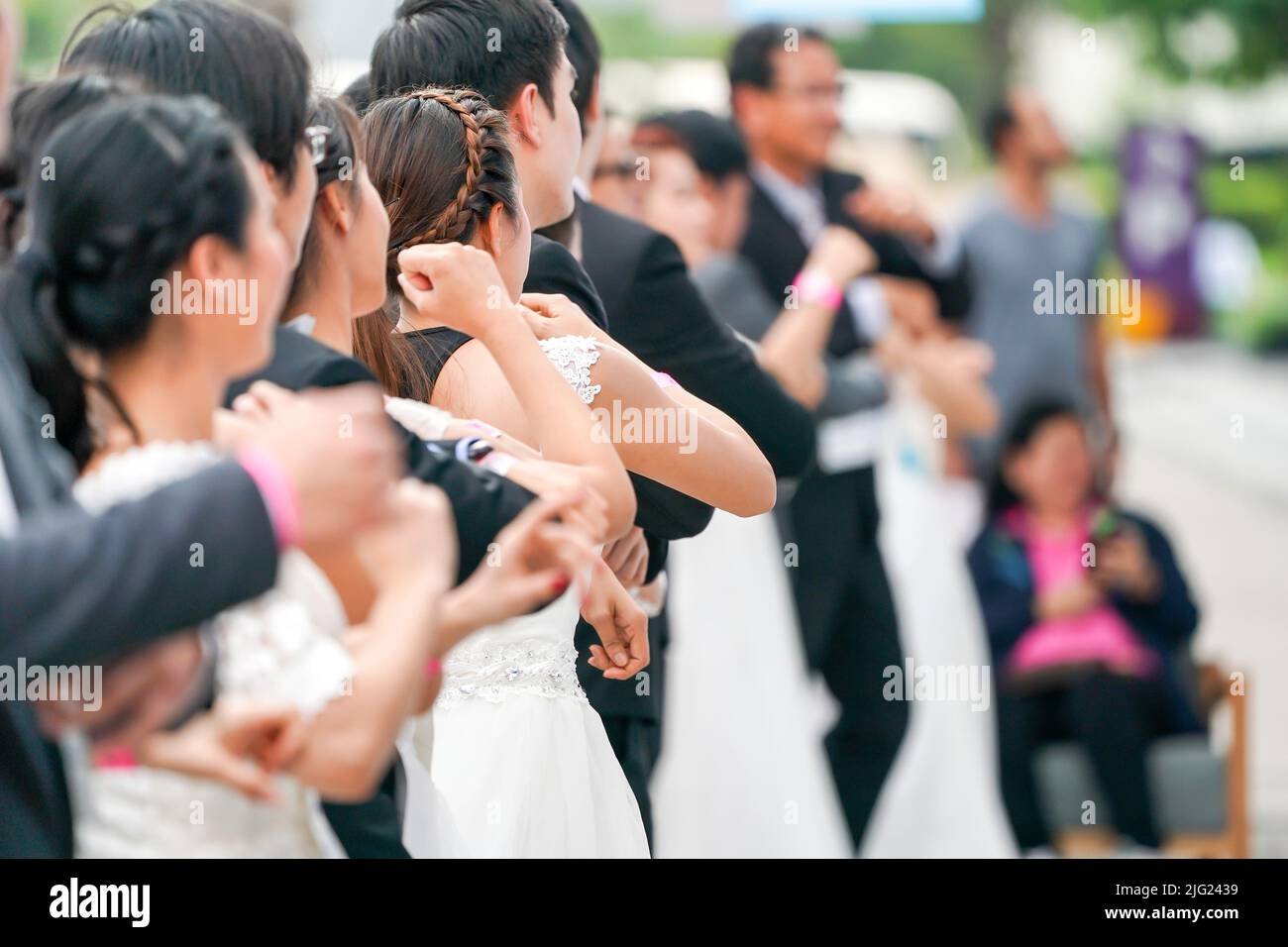 Verschiedene Bräute und Bräutigam wärmen sich an der Startlinie in Vorbereitung auf das Rennen, um zu gewinnen und die Zahlung für ihre ideale Hochzeit zu erhalten. Stockfoto