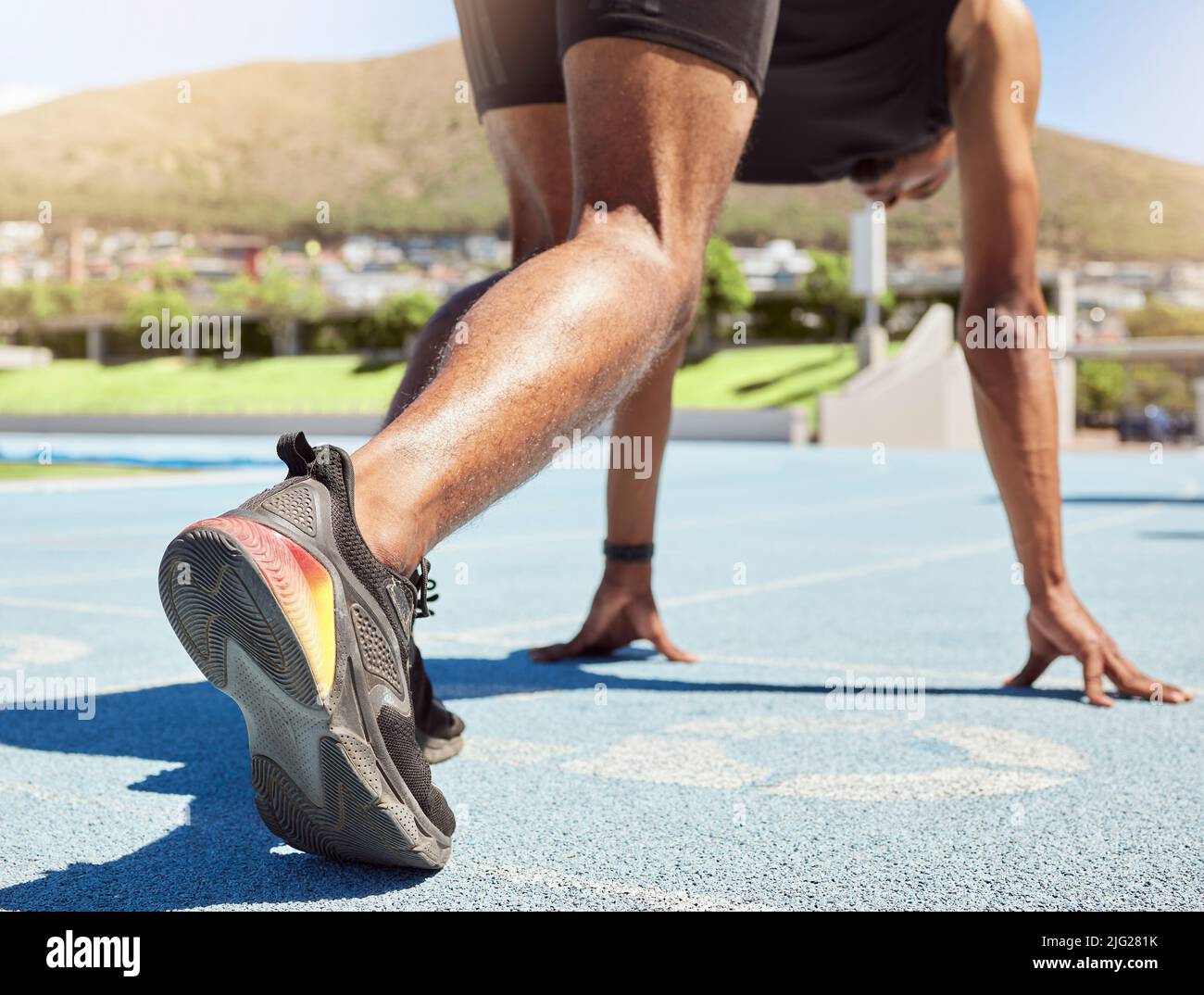 Nahaufnahme eines Sportlers, der sich bereit für das Laufen auf Kurs und Feld gemacht hat, mit seinen Füßen auf Startblöcken, die bereit sind, mit dem Sprinten zu beginnen. Nahaufnahme eines Mannes beim Start Stockfoto